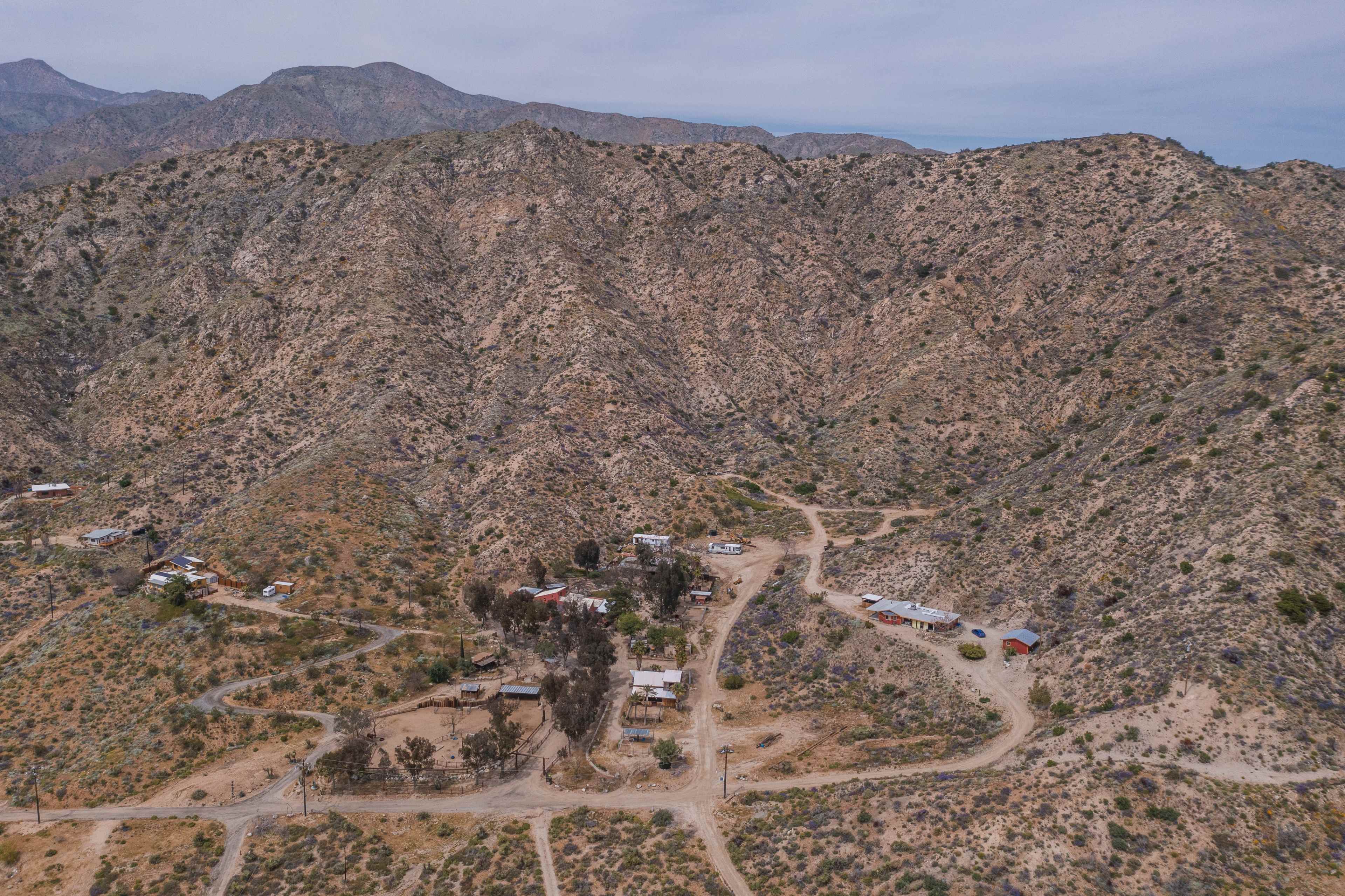 An aerial view of a small settlement surrounded by rugged mountainous terrain.