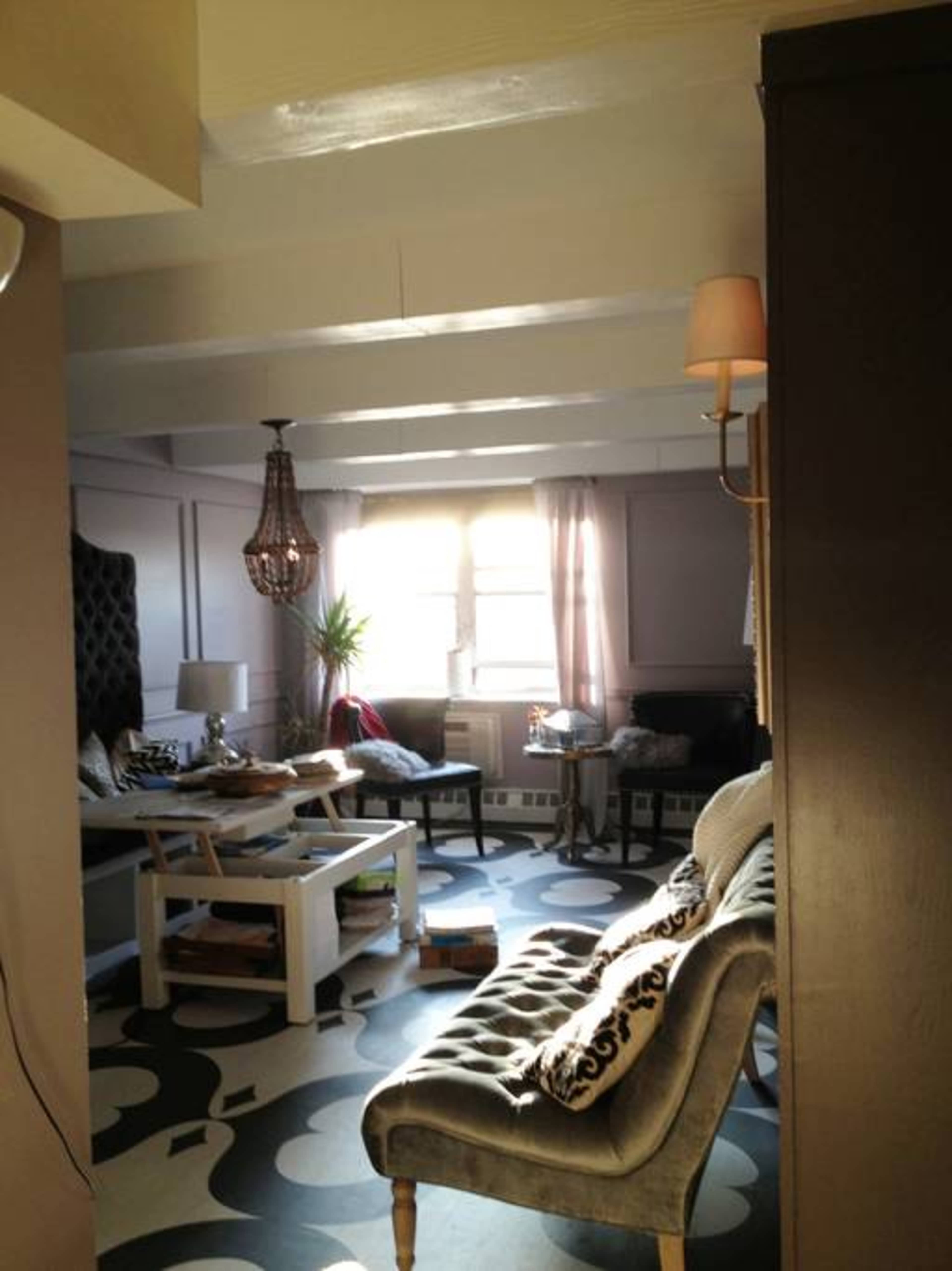 A living room with a patterned floor, a sofa, a coffee table, and large windows letting in natural light.