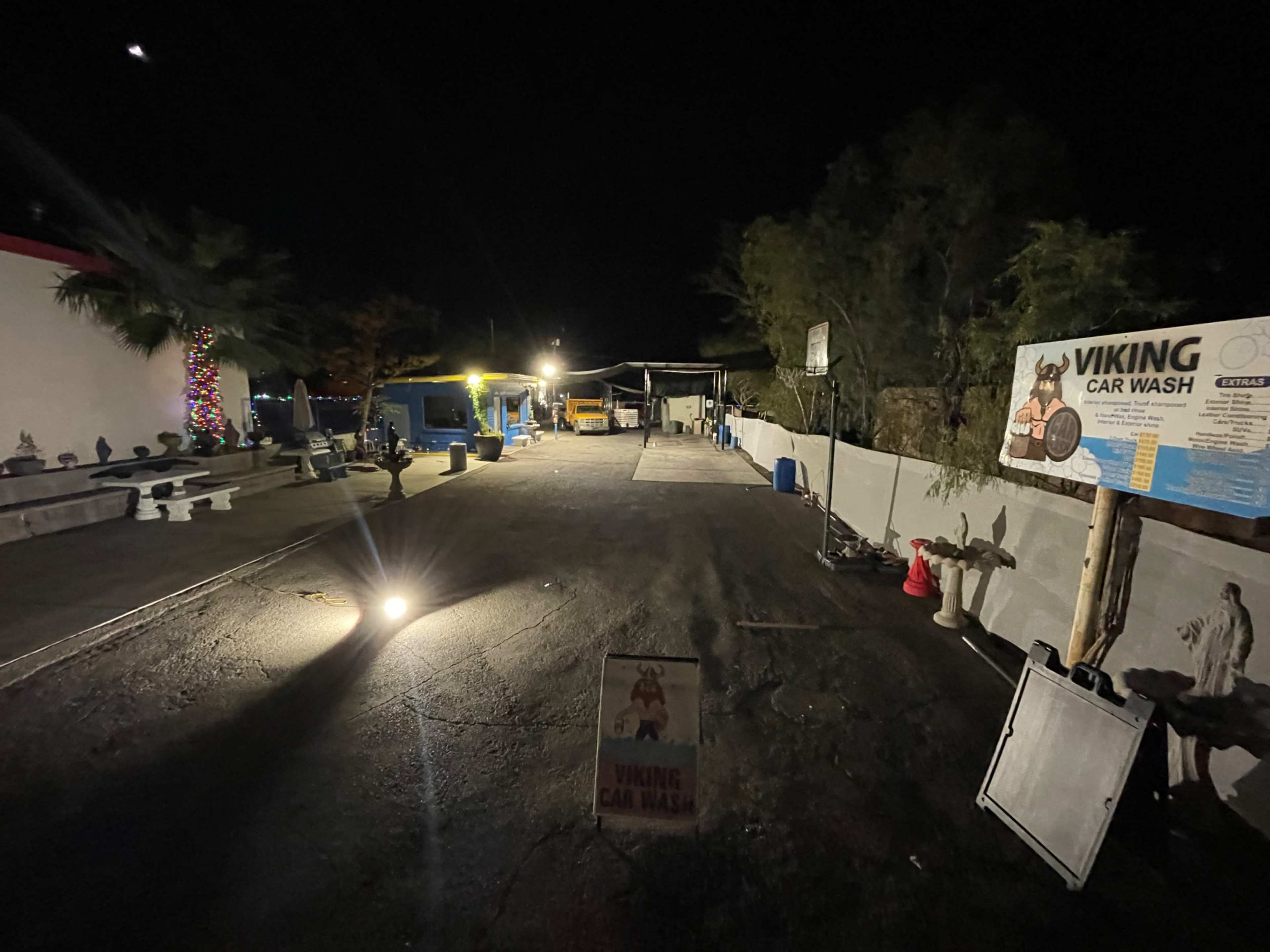 A dimly lit car wash area at night with various vehicles and signs, including one for "Viking Car Wash."