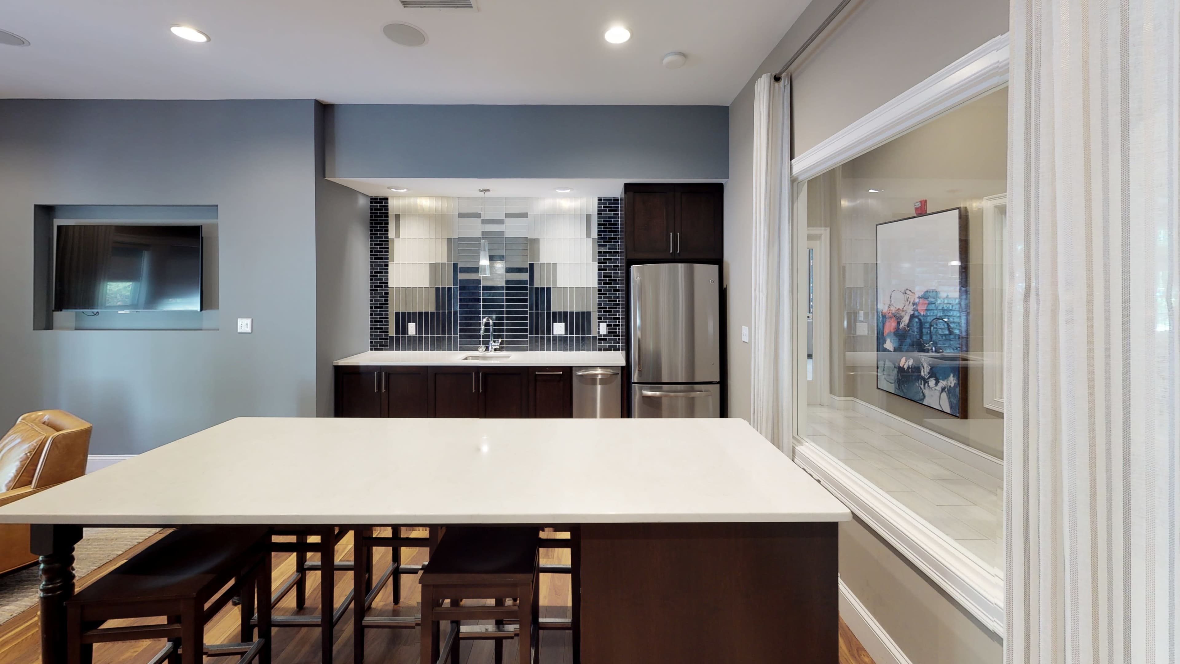 A modern kitchen features dark wooden cabinets, stainless steel appliances, and a large island with seating.