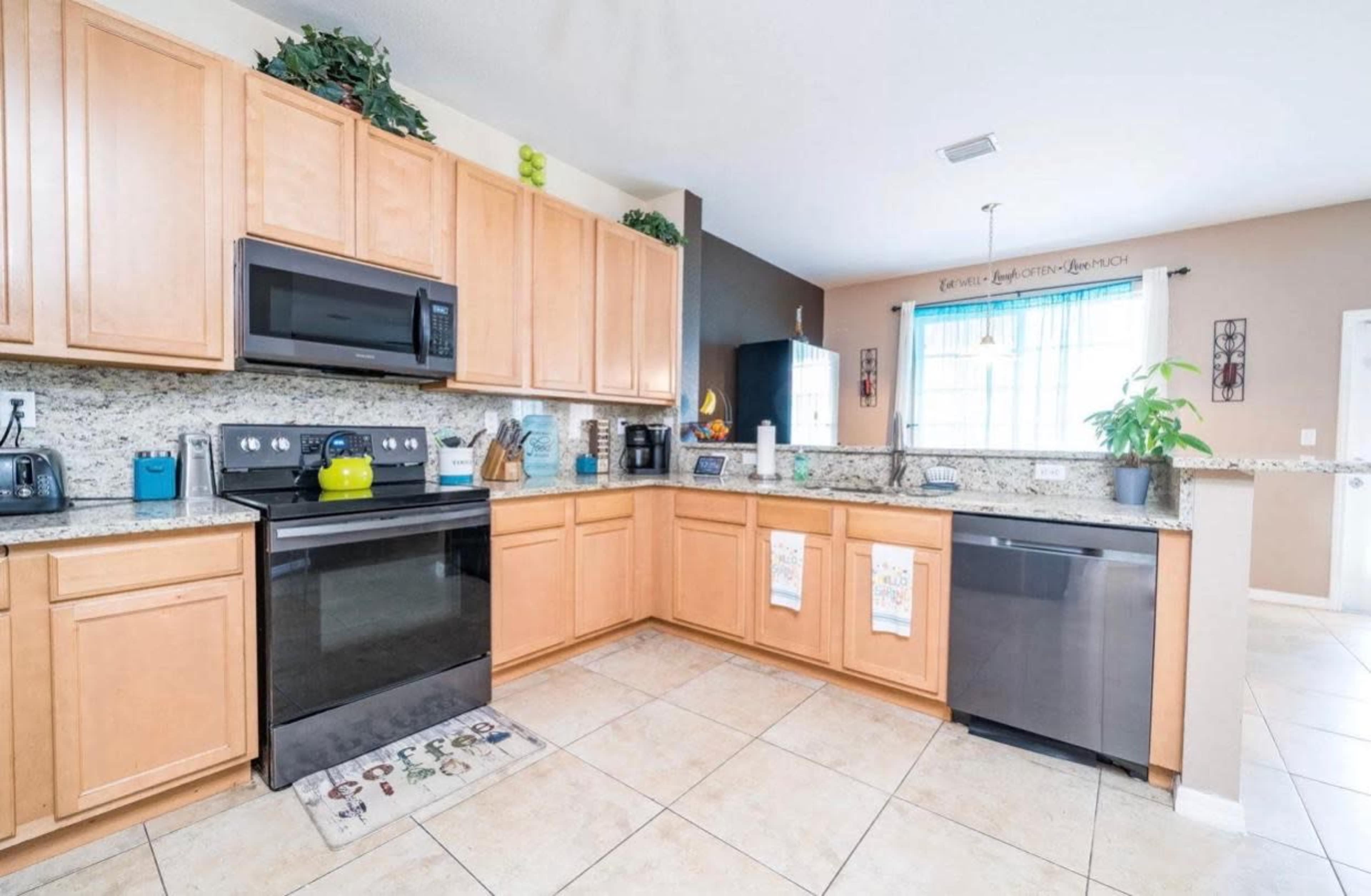The kitchen features wooden cabinets, granite countertops, and stainless steel appliances, with a window allowing natural light.