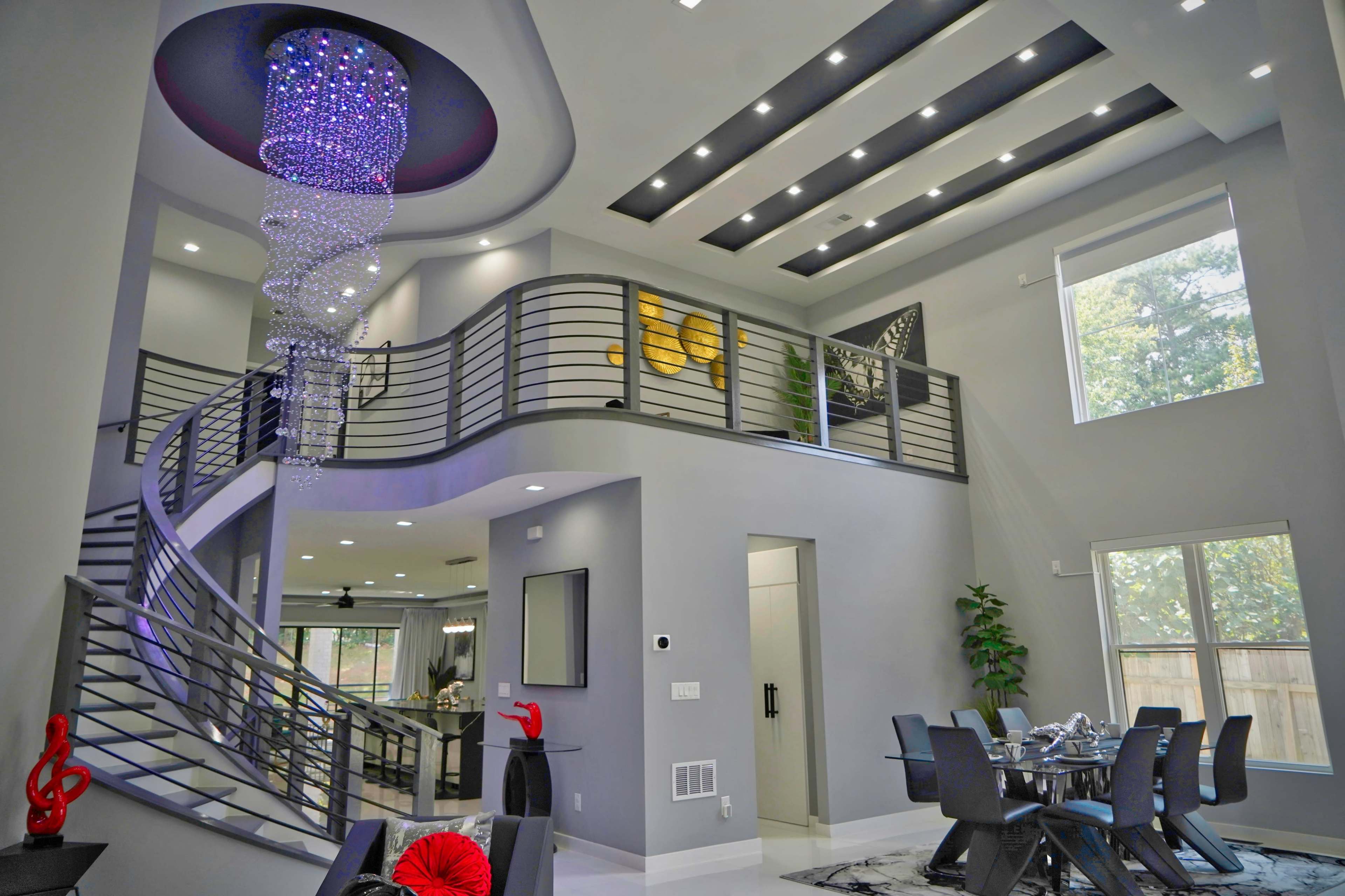 A modern interior featuring a spiral staircase, a large chandelier, and a dining area with sleek furniture.