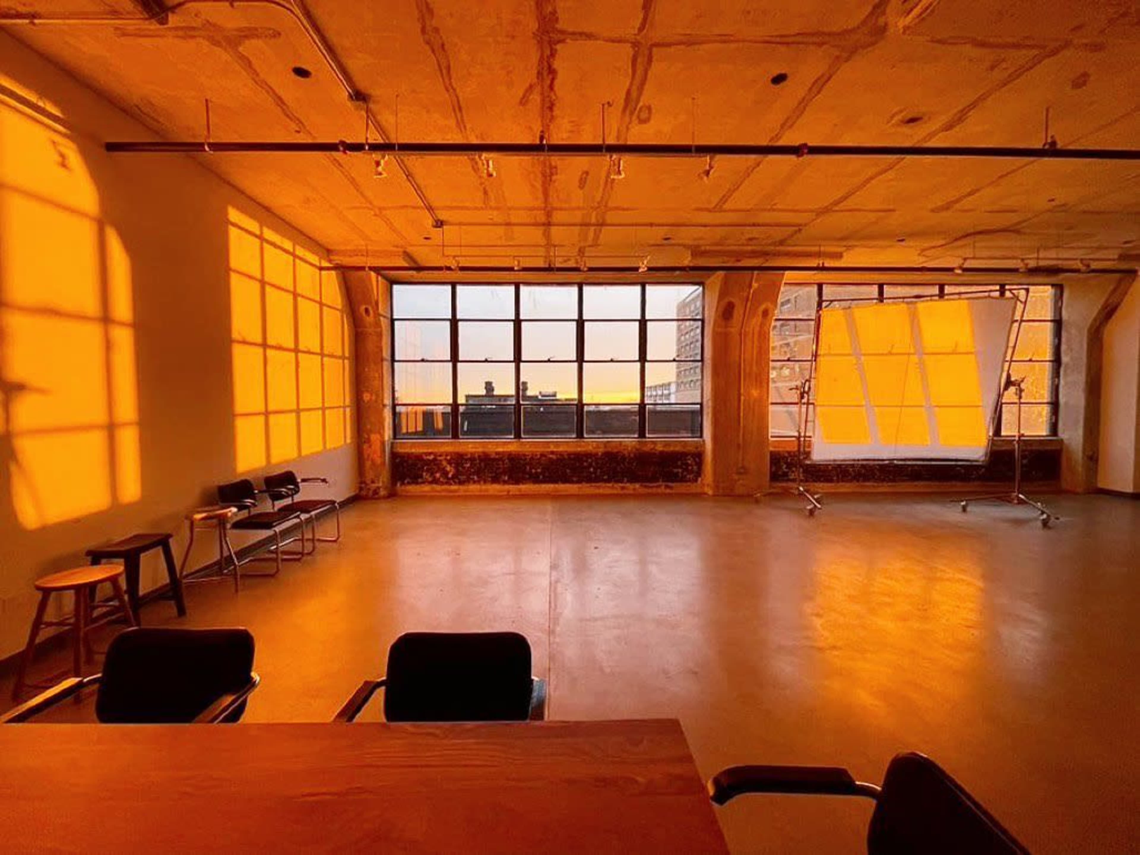 A spacious, empty room with large windows casting golden light onto the walls and floor.