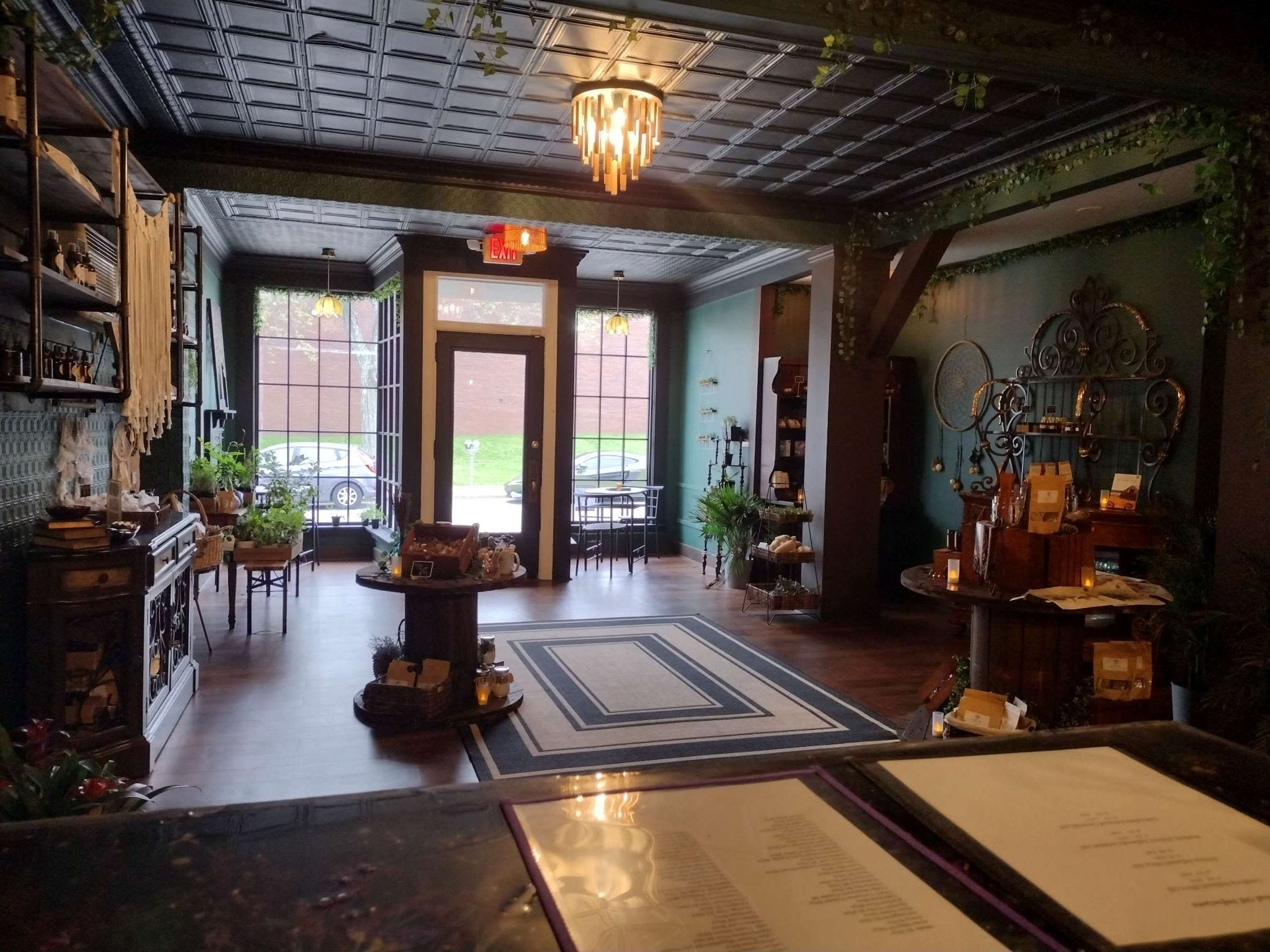 A well-decorated boutique shop interior with wooden furniture, plants, and a counter in the foreground.