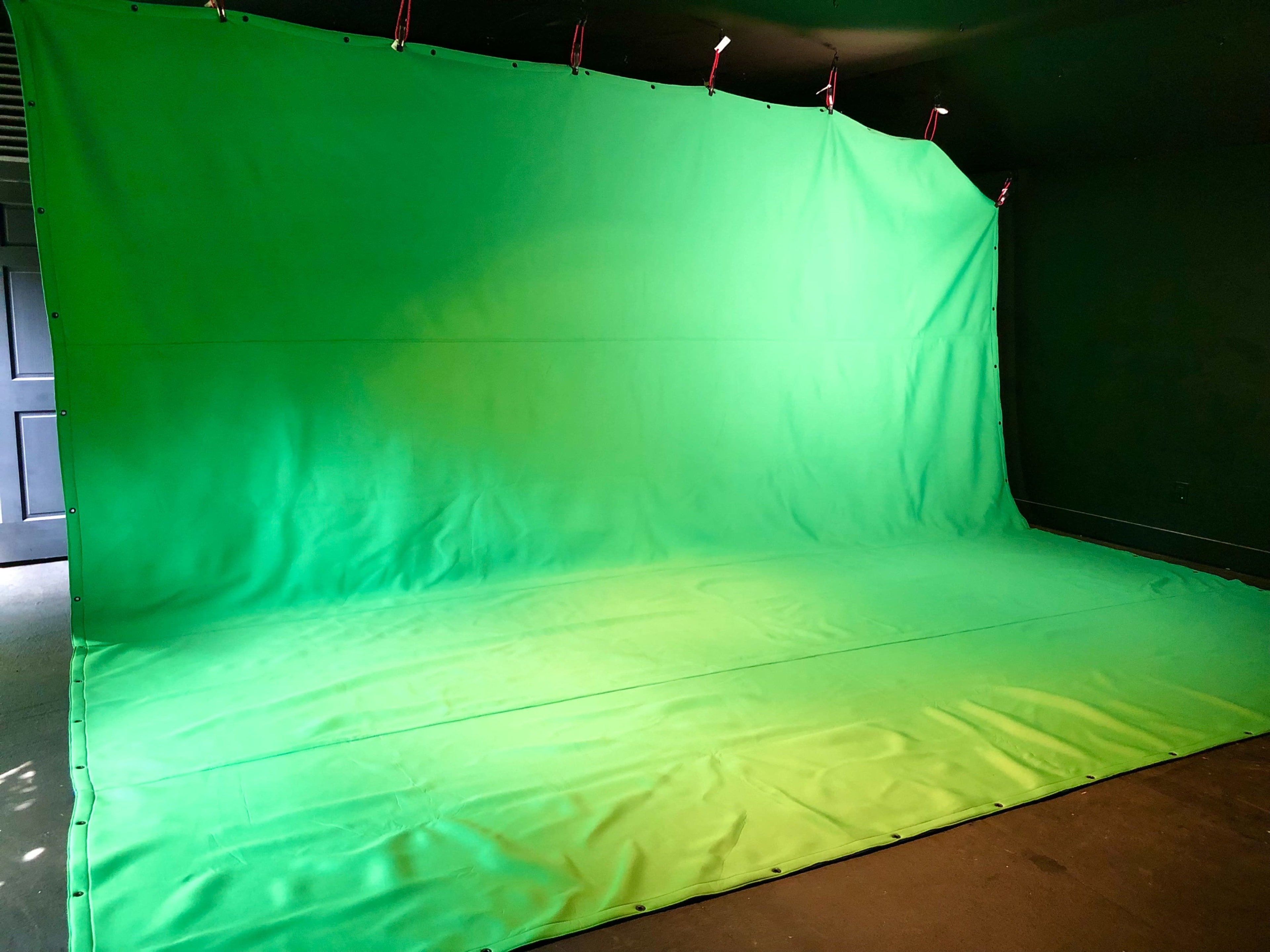 A large green backdrop draped across a wall and floor, commonly used for chroma key photography or video production.