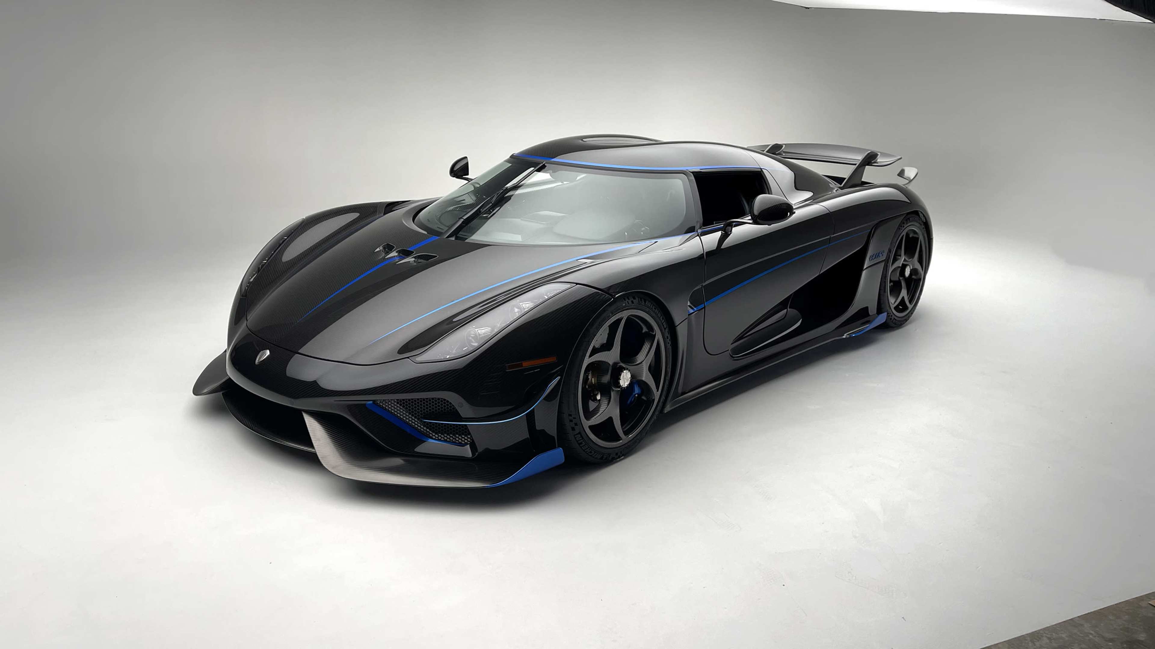 A sleek black sports car with blue accents is positioned on a neutral background in a well-lit studio.