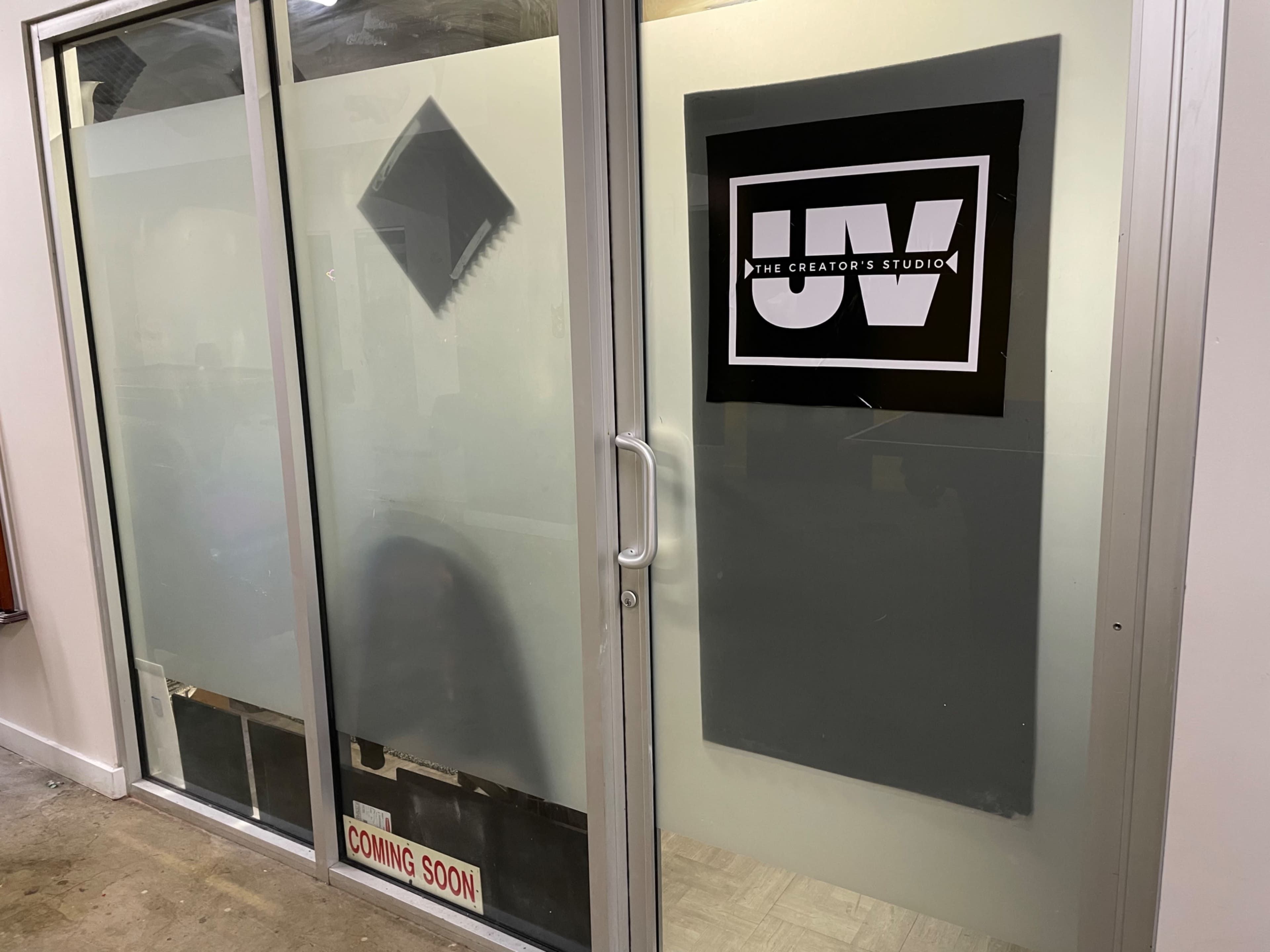 A glass storefront with a sign reading "THE CREATOR'S STUDIO" and a "COMING SOON" notice at the bottom.
