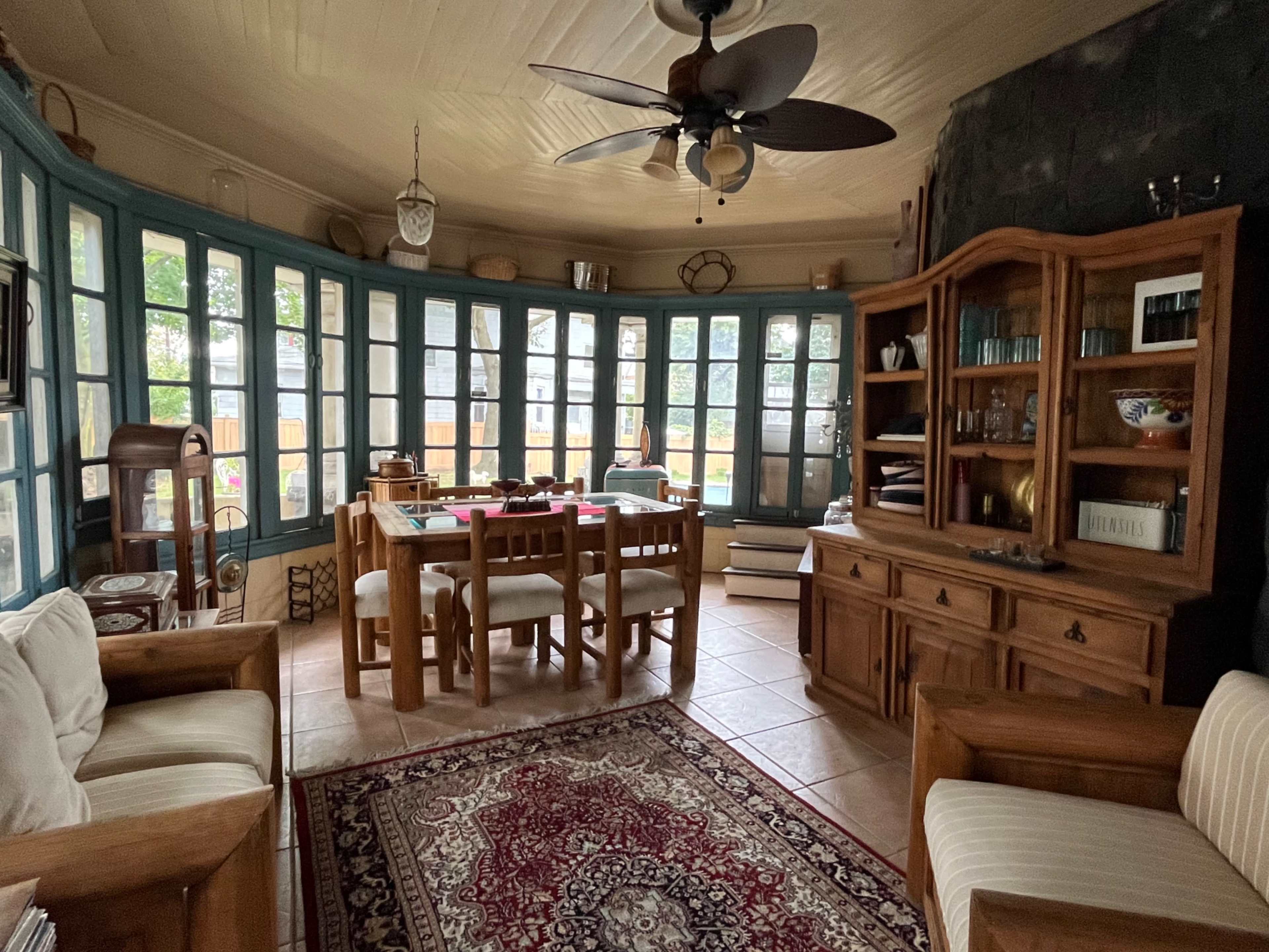 A solarium features a dining table, wooden furniture, and large windows allowing natural light in.