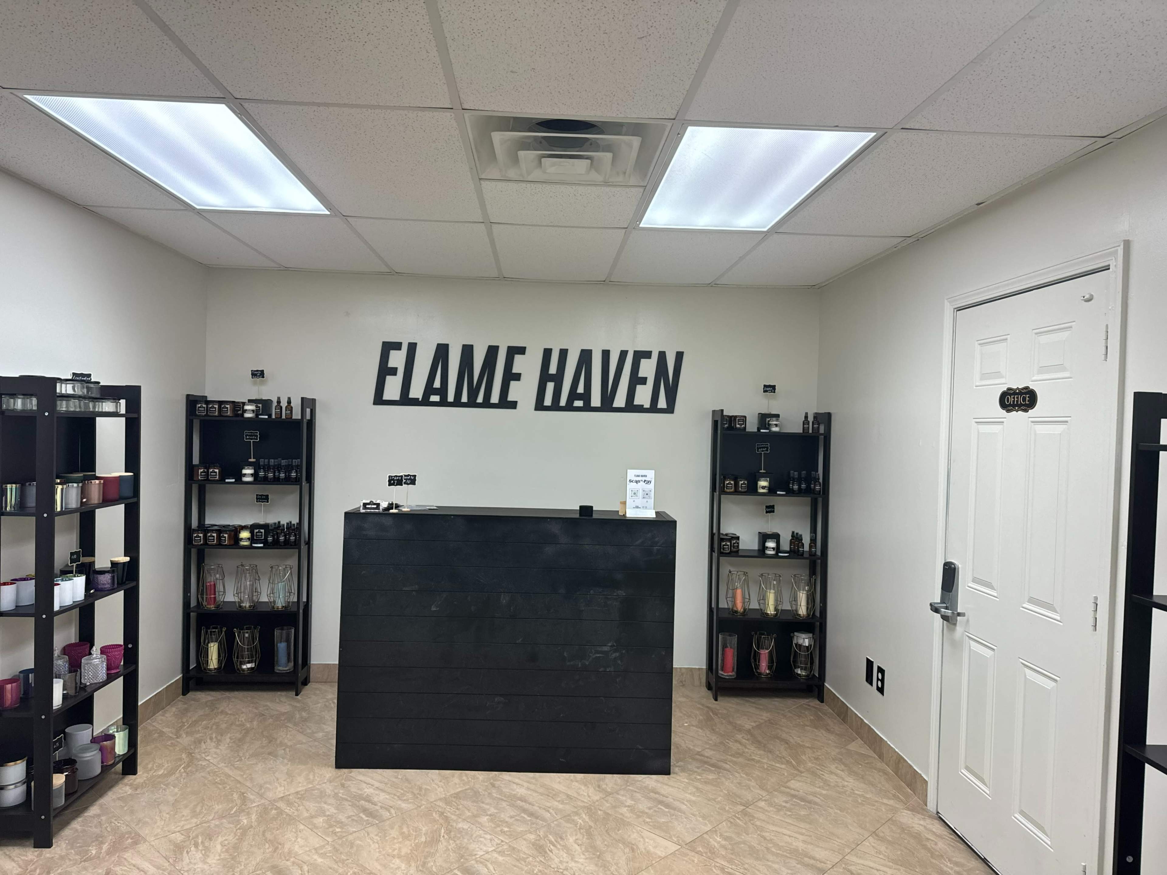 A minimalist retail space named "FLAME HAVEN," featuring a dark reception counter and shelves lined with various candles and fragrances.