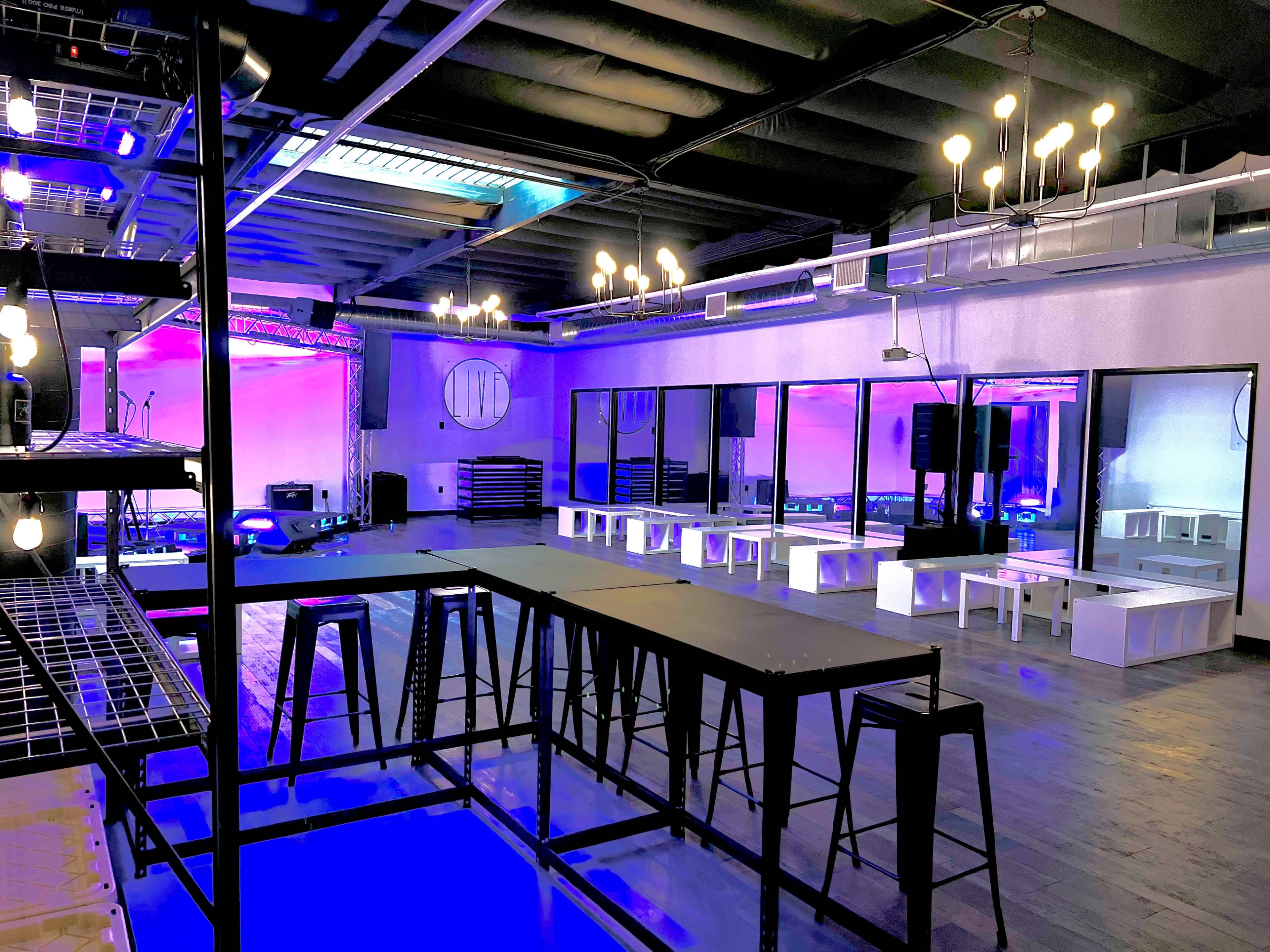 A modern event space with seating areas, a stage, and colorful lighting.