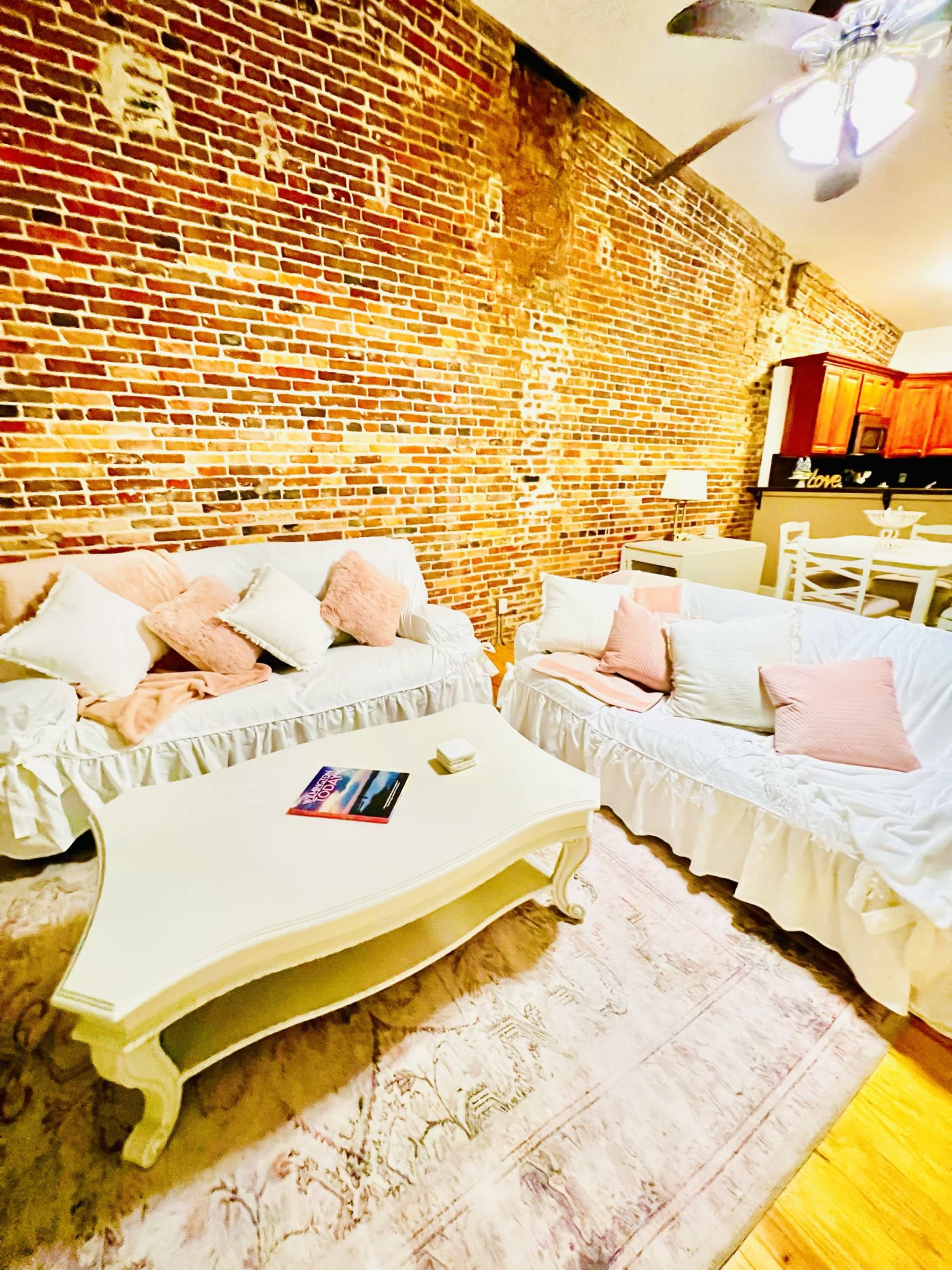 A cozy living space with two sofas, a coffee table, and a brick wall in the background.