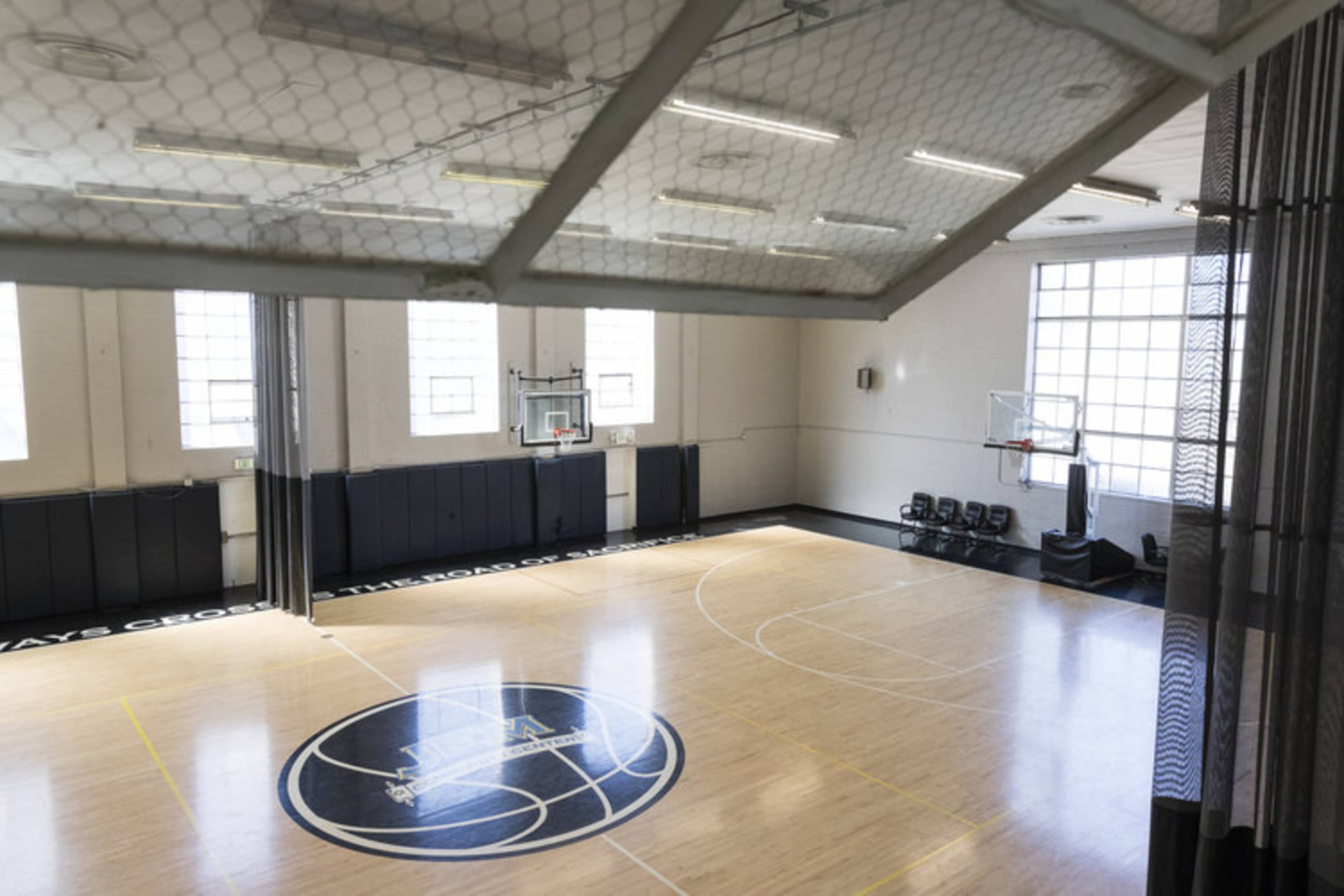 A spacious basketball court with a wooden floor, marked lines, and basketball hoops at each end.