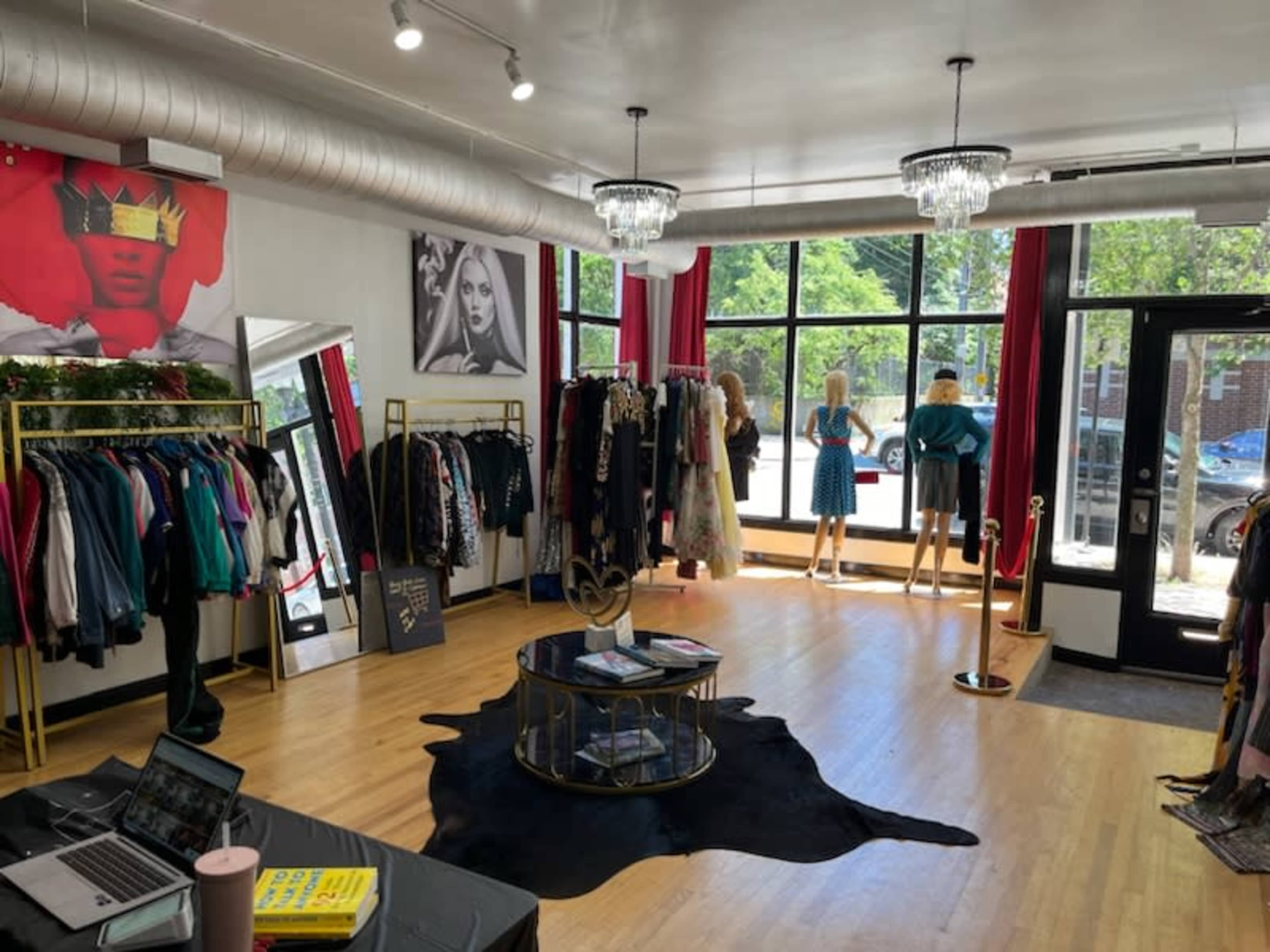 The image shows the interior of a boutique featuring clothing racks, mannequins in stylish outfits, and large windows allowing natural light to fill the space.