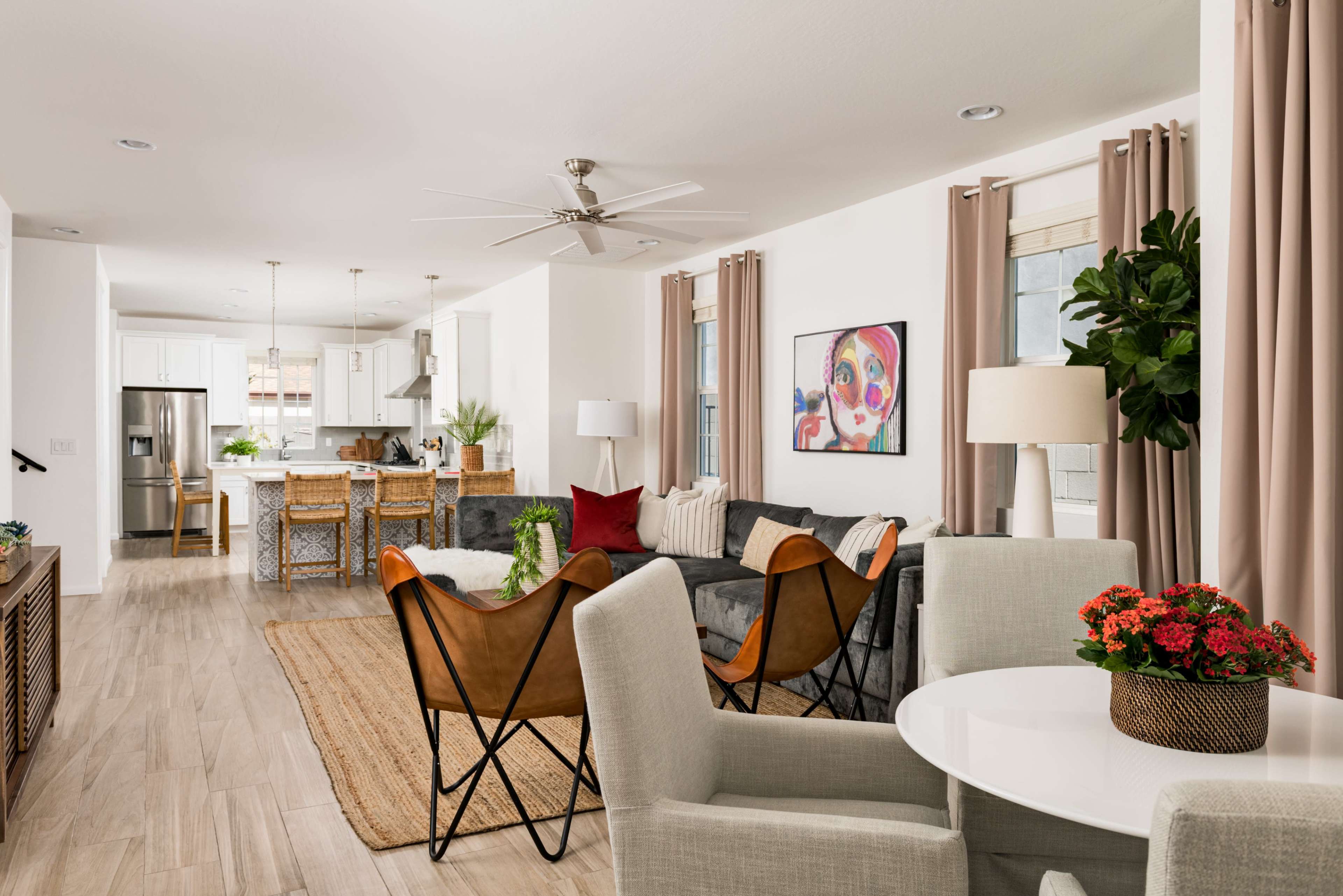 A modern, open-concept living area with a kitchen, seating area, and dining space, featuring light-colored walls and furnishings.