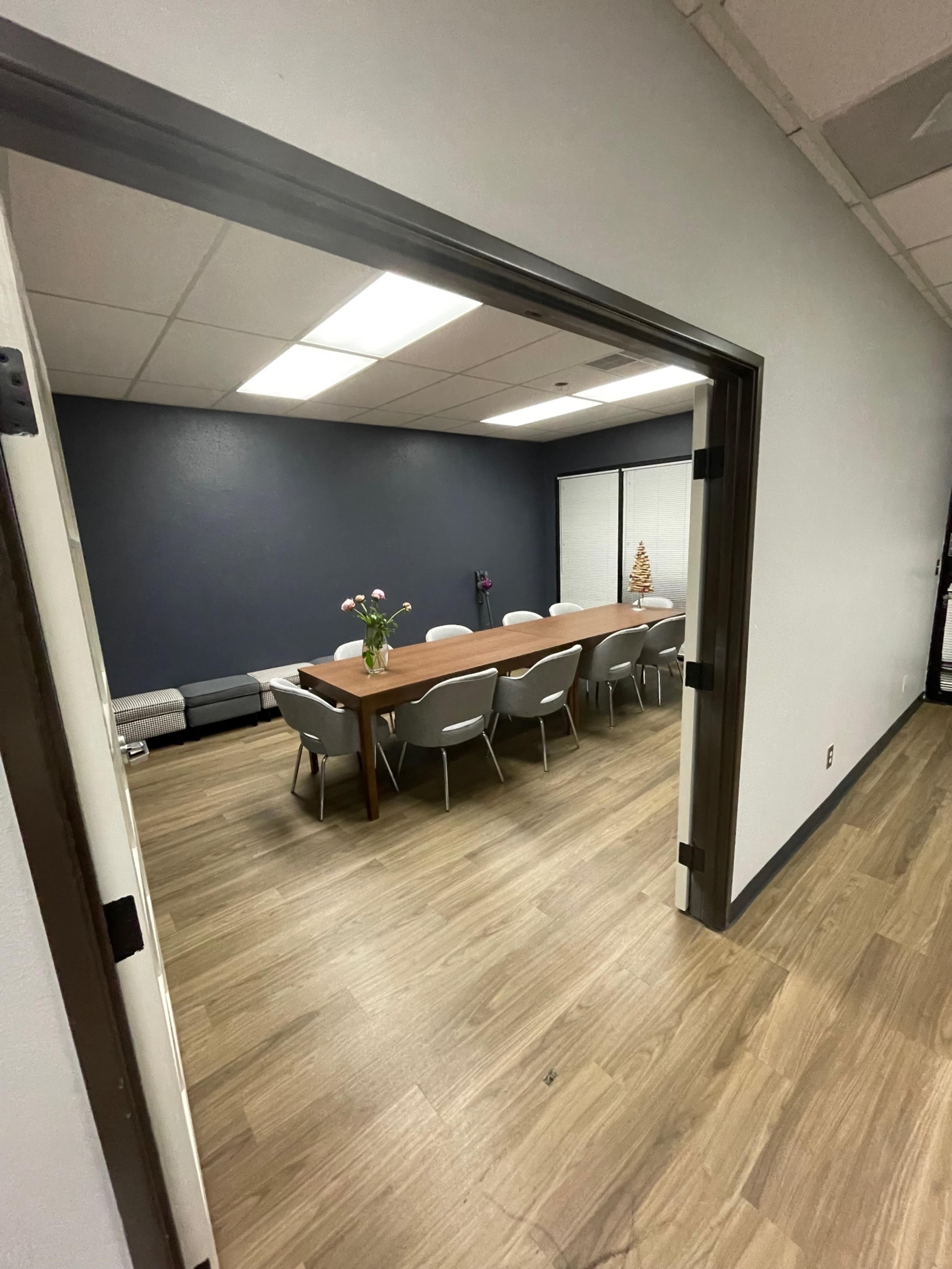 The image shows a conference room with a long table and chairs, viewed from an open doorway.