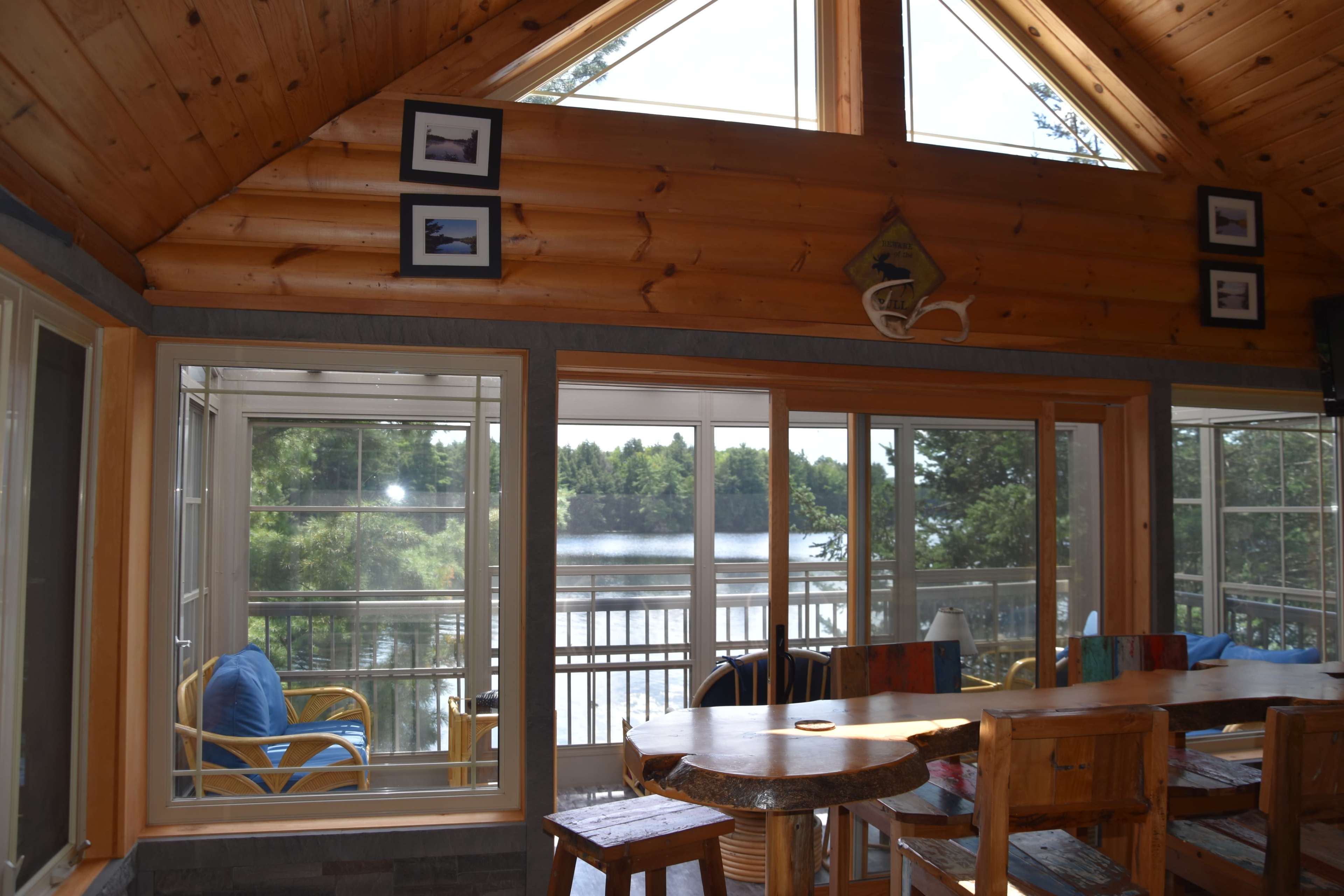 A spacious wooden interior of a cabin featuring large windows that overlook a lake.