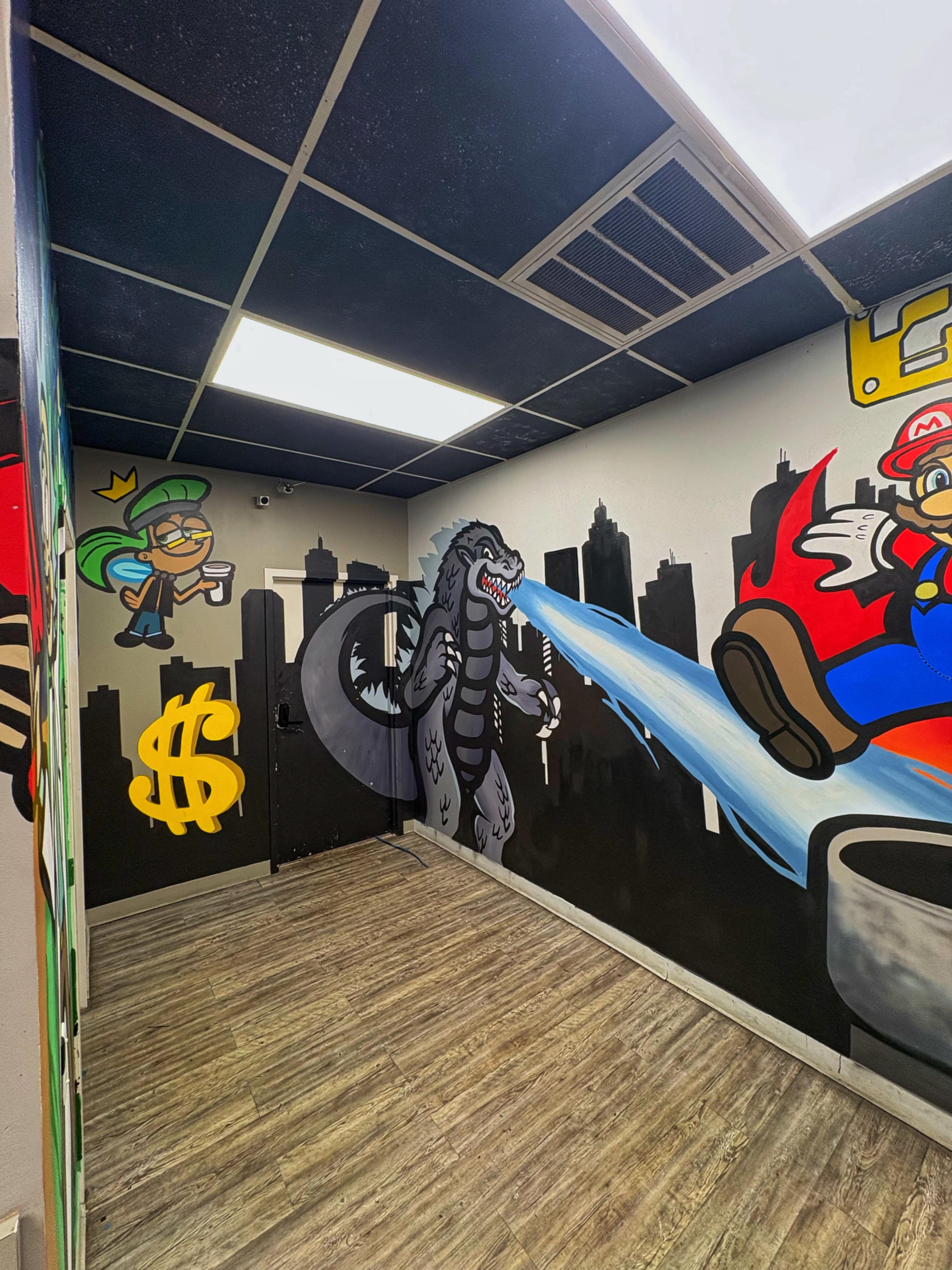 The image shows a brightly painted room featuring mural art of a dragon-like creature, a character resembling a video game plumber, and a green character holding money, with urban skyline outlines on the walls.
