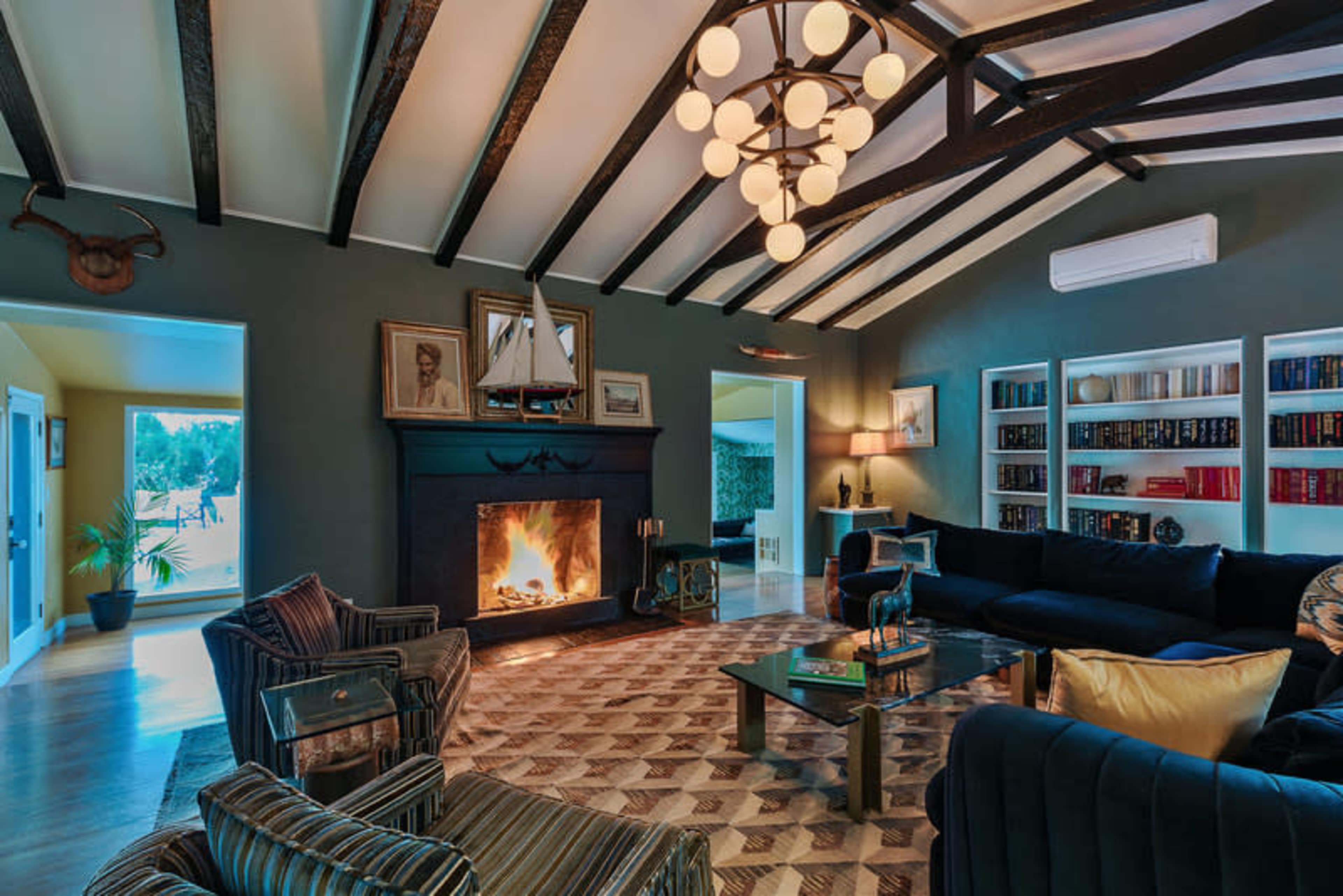 The living room features a fireplace, a coffered ceiling, and bookshelves along one wall.