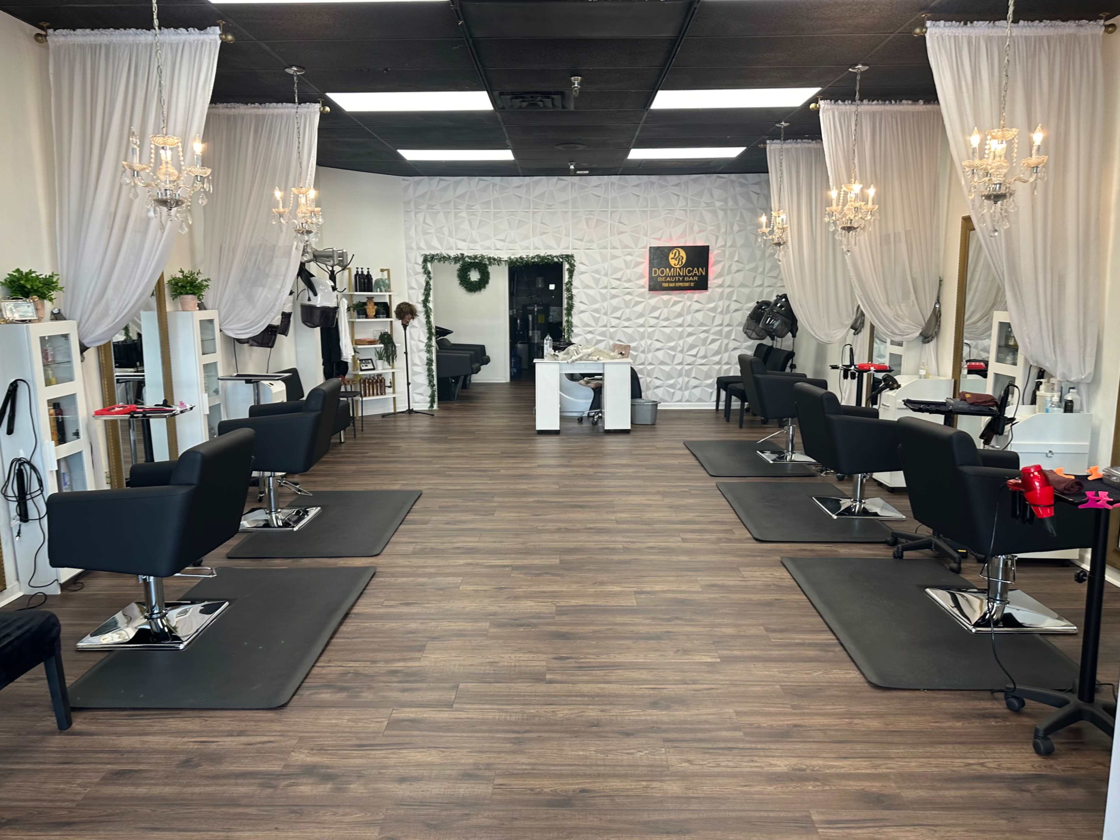 The image shows a hair salon interior with styling stations, black chairs, and elegant chandeliers.