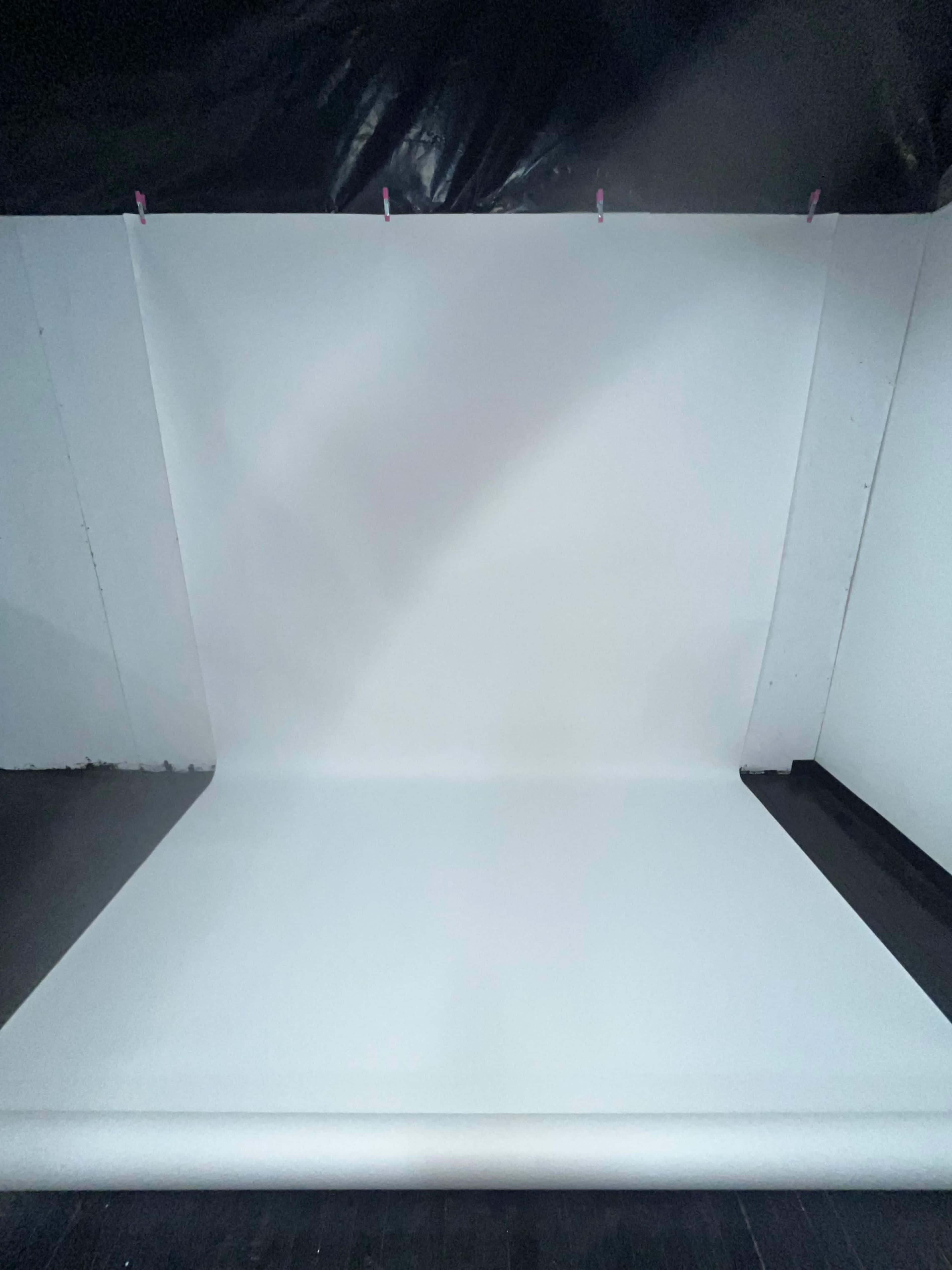 The image shows a blank white backdrop set up in a studio environment.