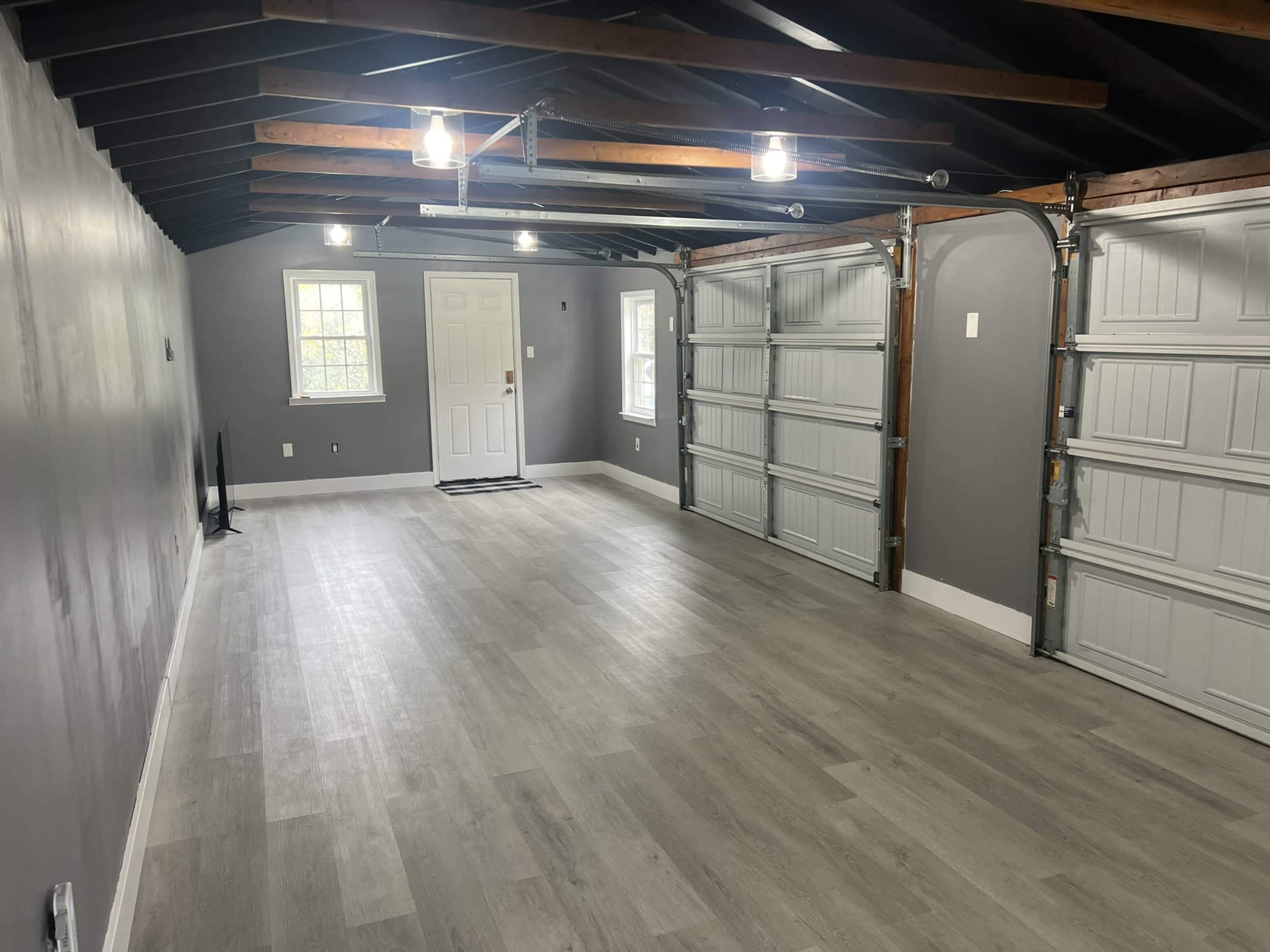 A spacious garage with gray walls, light-colored flooring, and two large garage doors on one side.