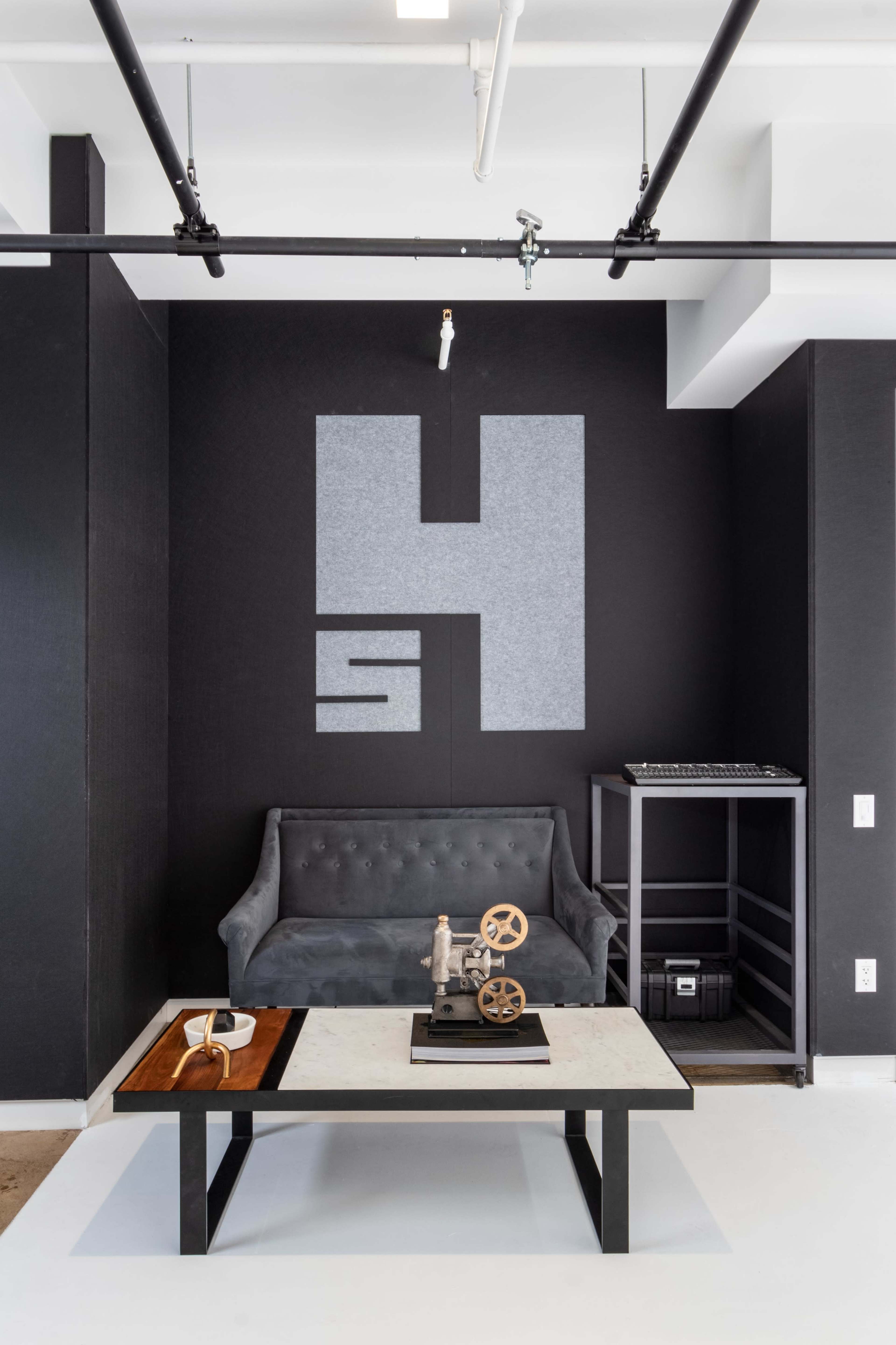 A modern interior with a gray sofa, a coffee table featuring decorative items, and a large abstract design on the wall.
