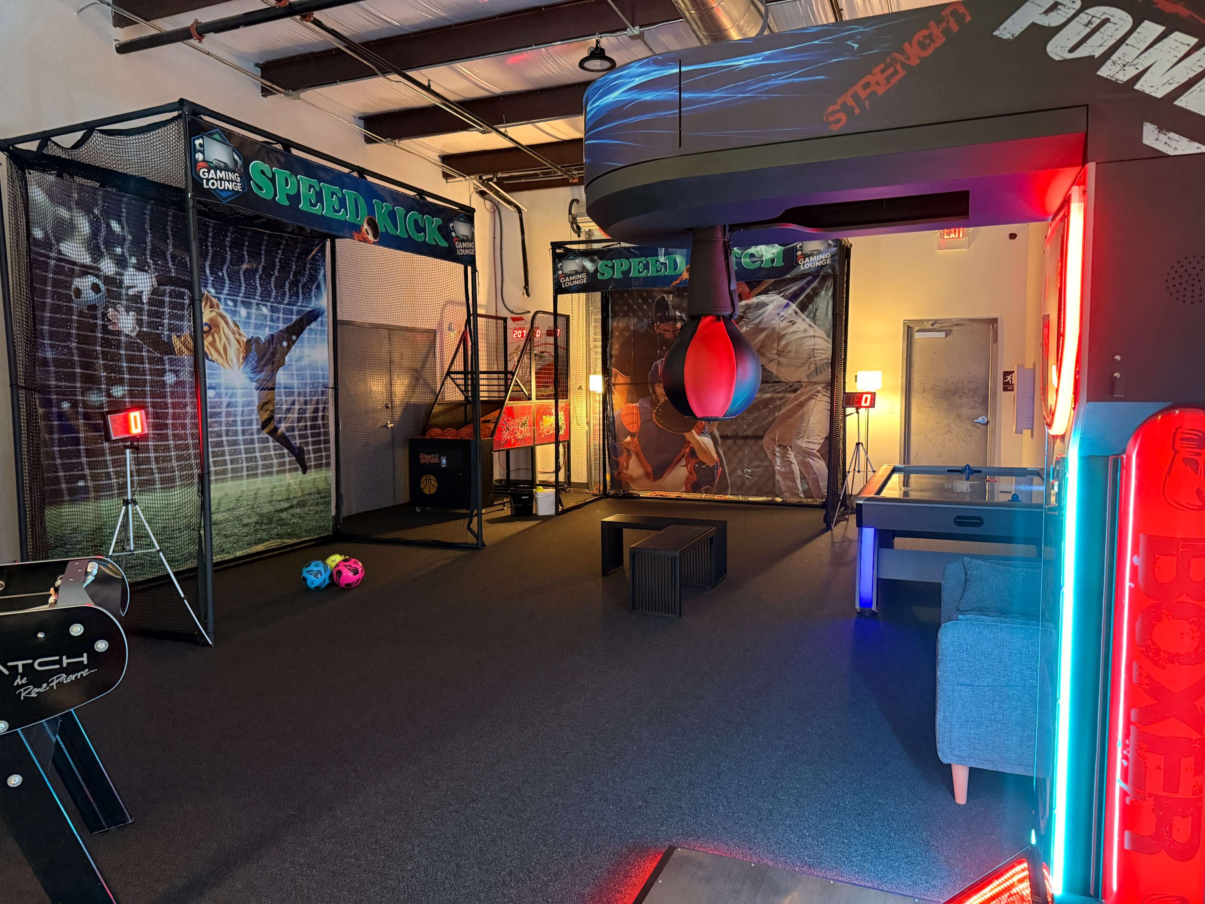 The image depicts an indoor sports entertainment area featuring a speed kick soccer game, a punching bag station, and colorful lighting.