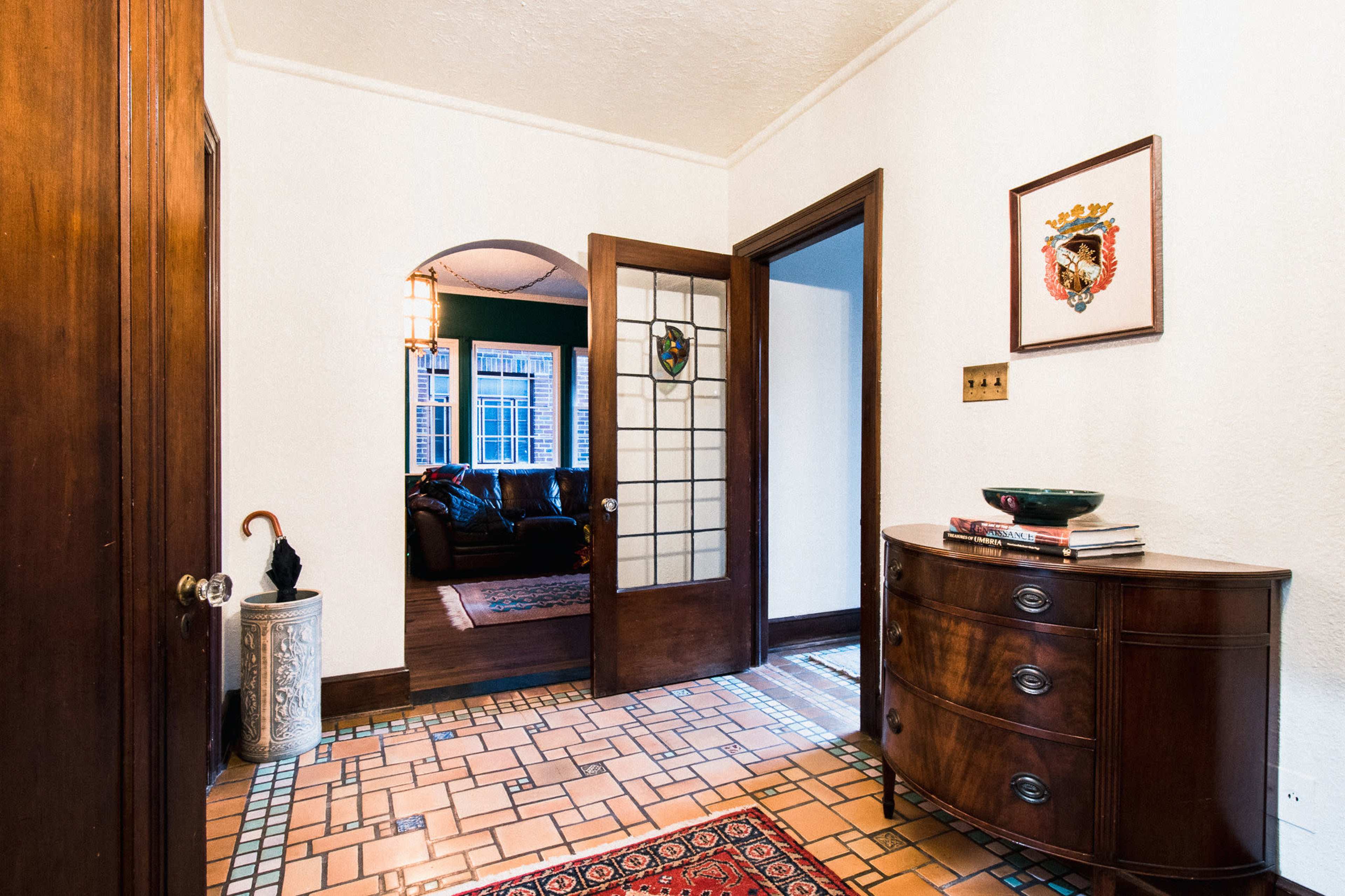 A hallway with a curved archway leading to a living room, featuring a wooden console table and decorative artwork on the walls.