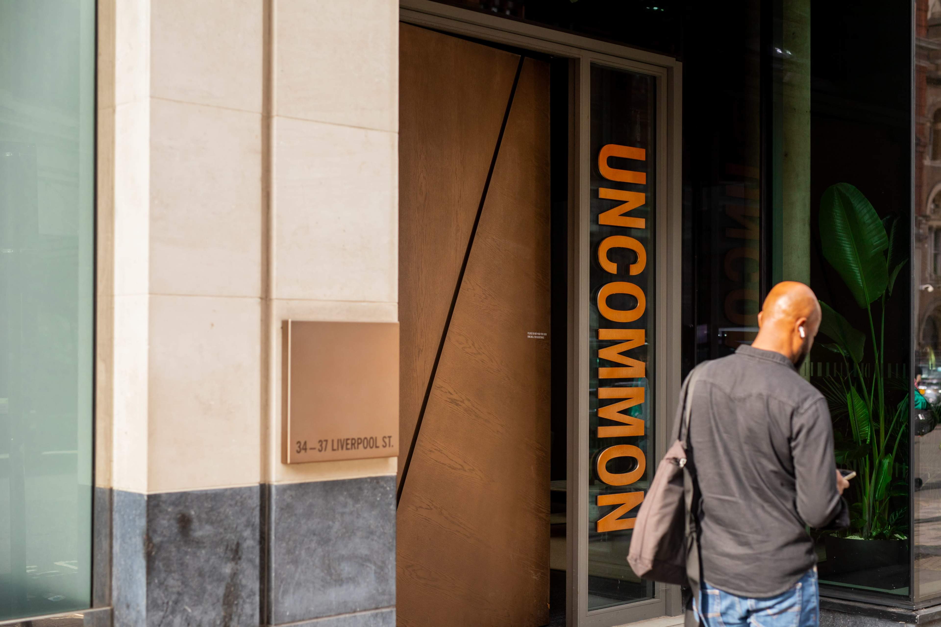 A person stands outside a building with a large door labeled "UNCOMMON," located at 34-37 Liverpool Street.
