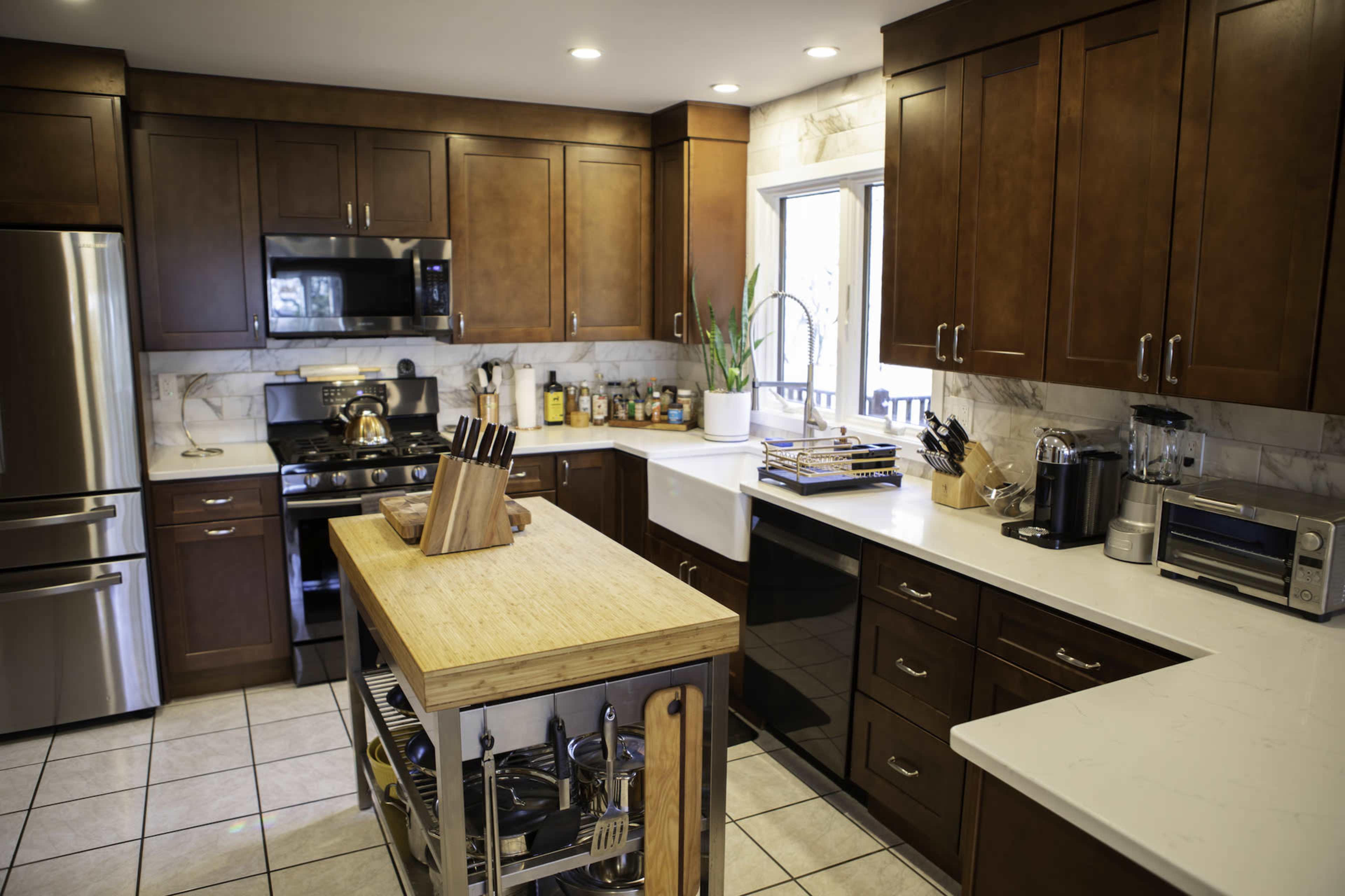 The kitchen features wooden cabinets, stainless steel appliances, and a central island with a wooden top and storage underneath.