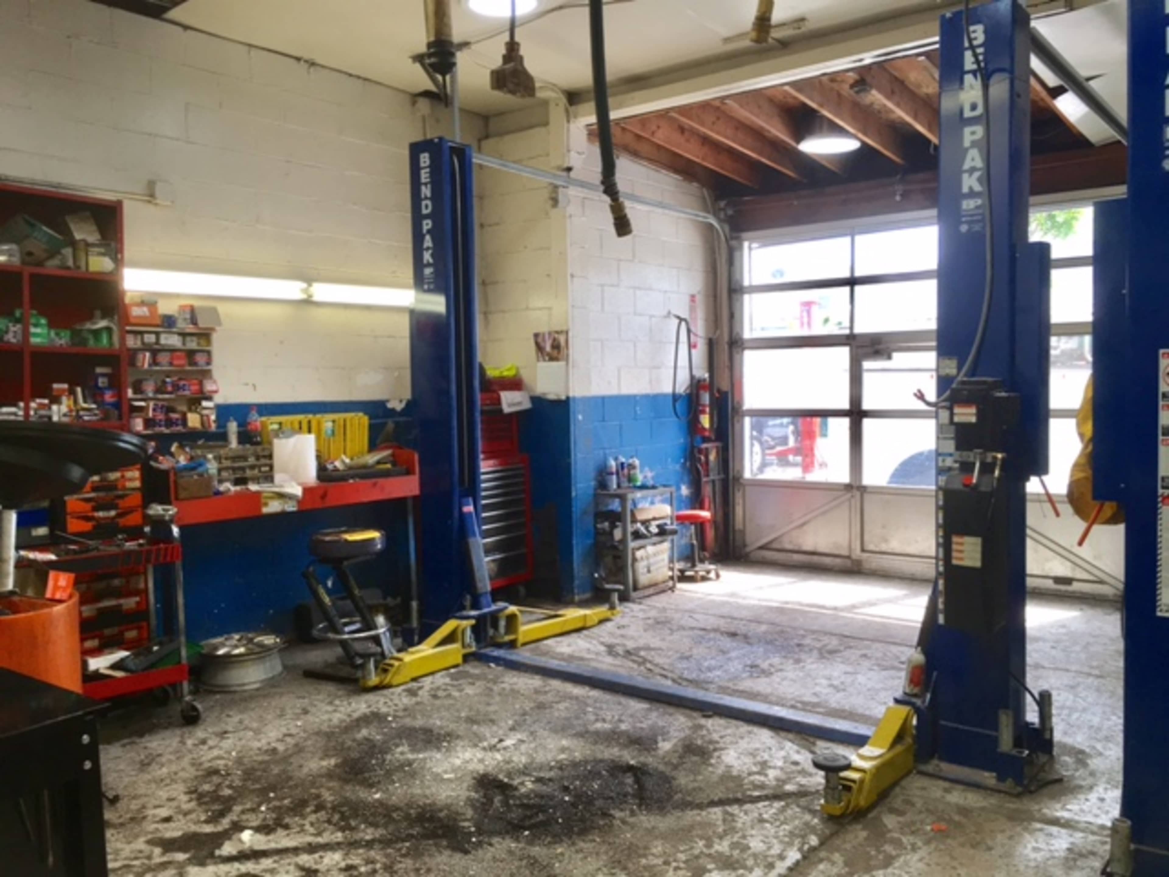 A well-equipped auto repair shop with two vehicle lifts and various tools organized on red and blue shelves.