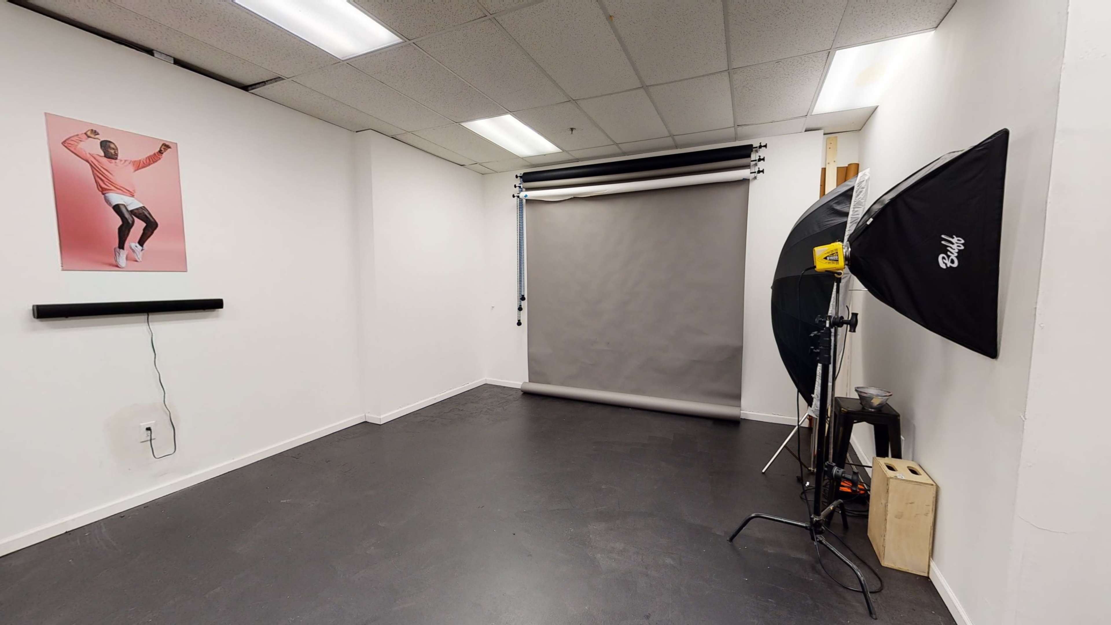 A photography studio with a large backdrop, lighting equipment, and a poster on the wall.