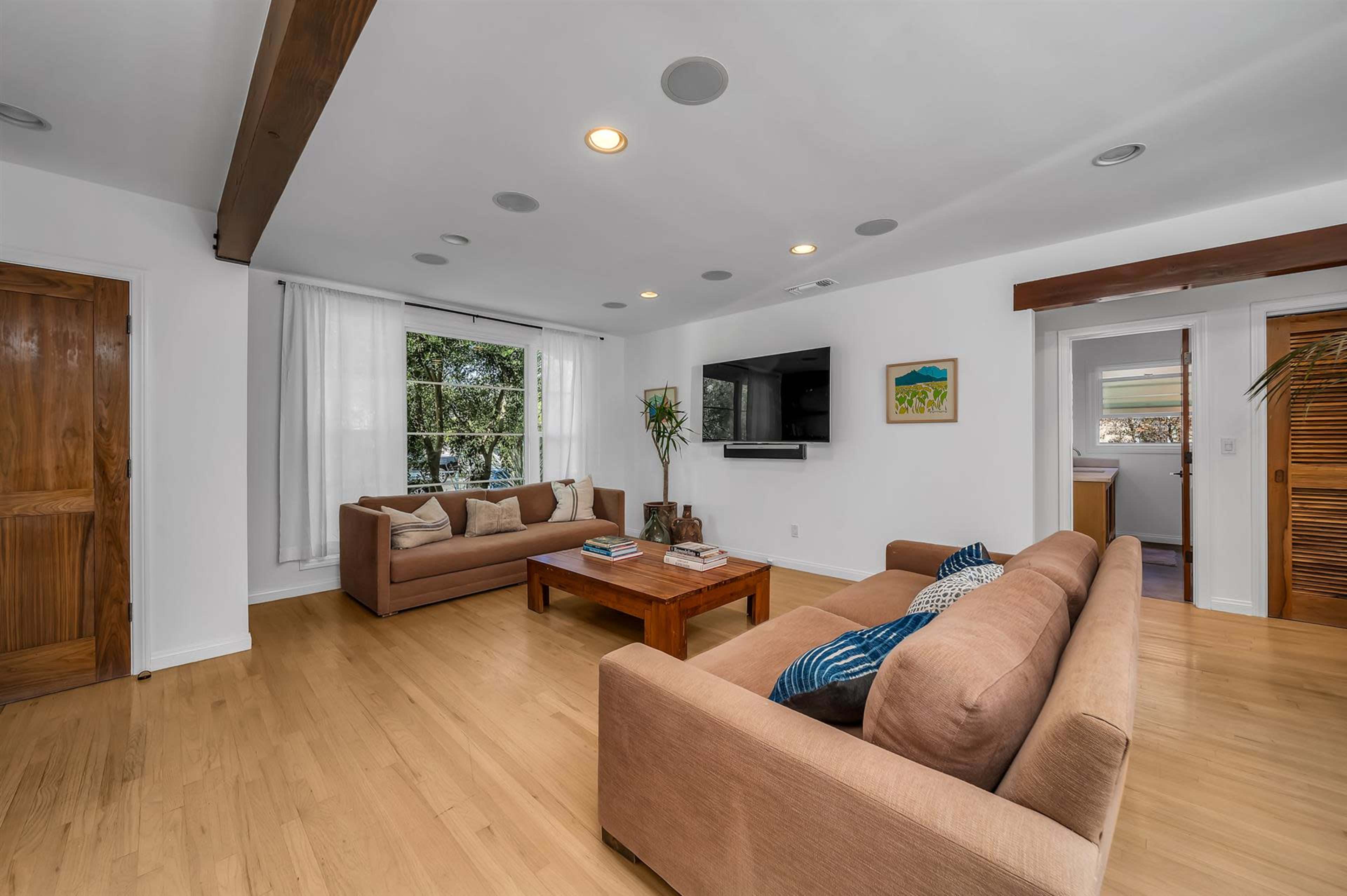 A bright, modern living room with a wooden coffee table and two sofas facing a mounted television.