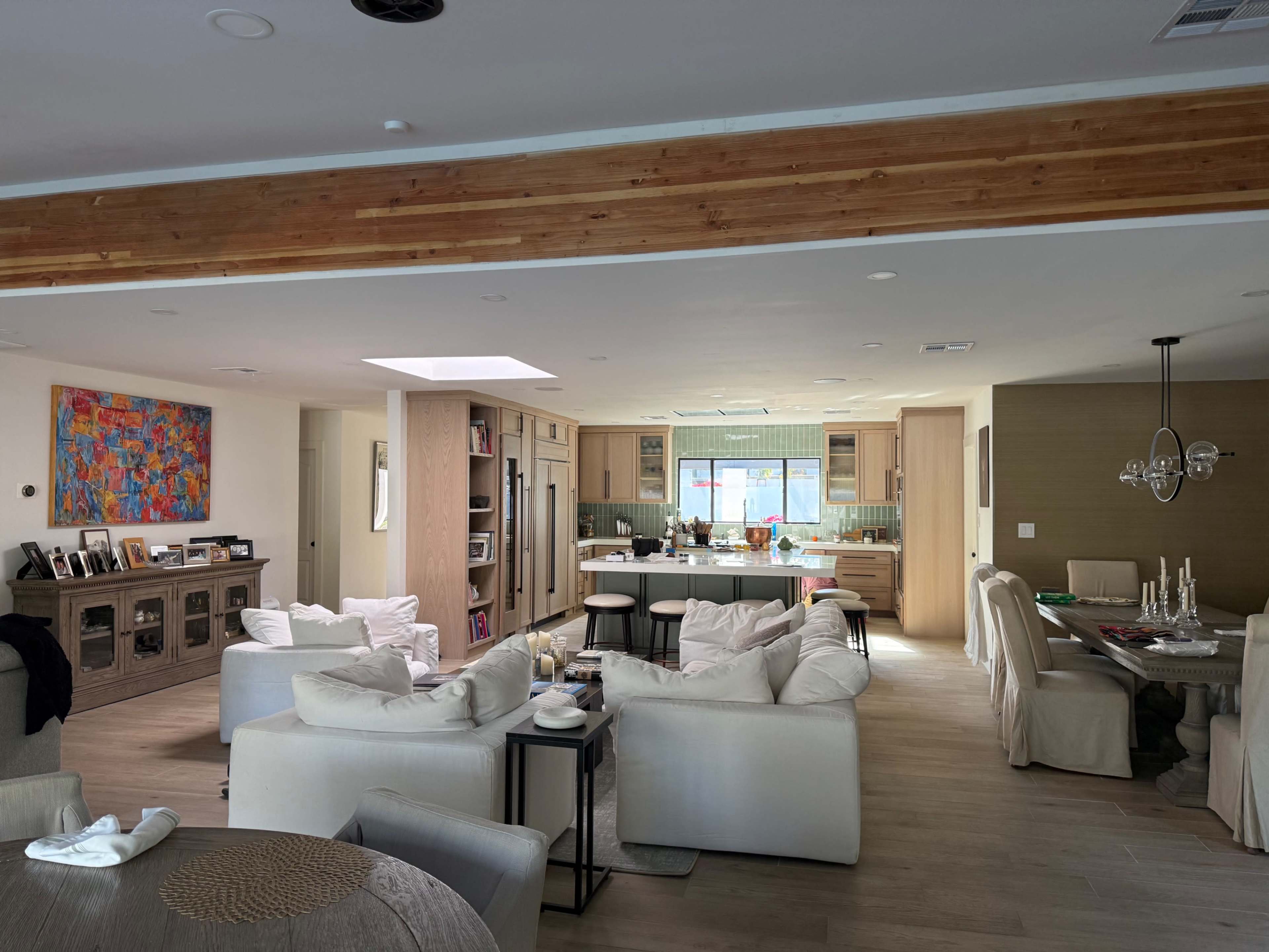 The image shows a bright, open-concept kitchen and living area with modern furnishings and a dining space.