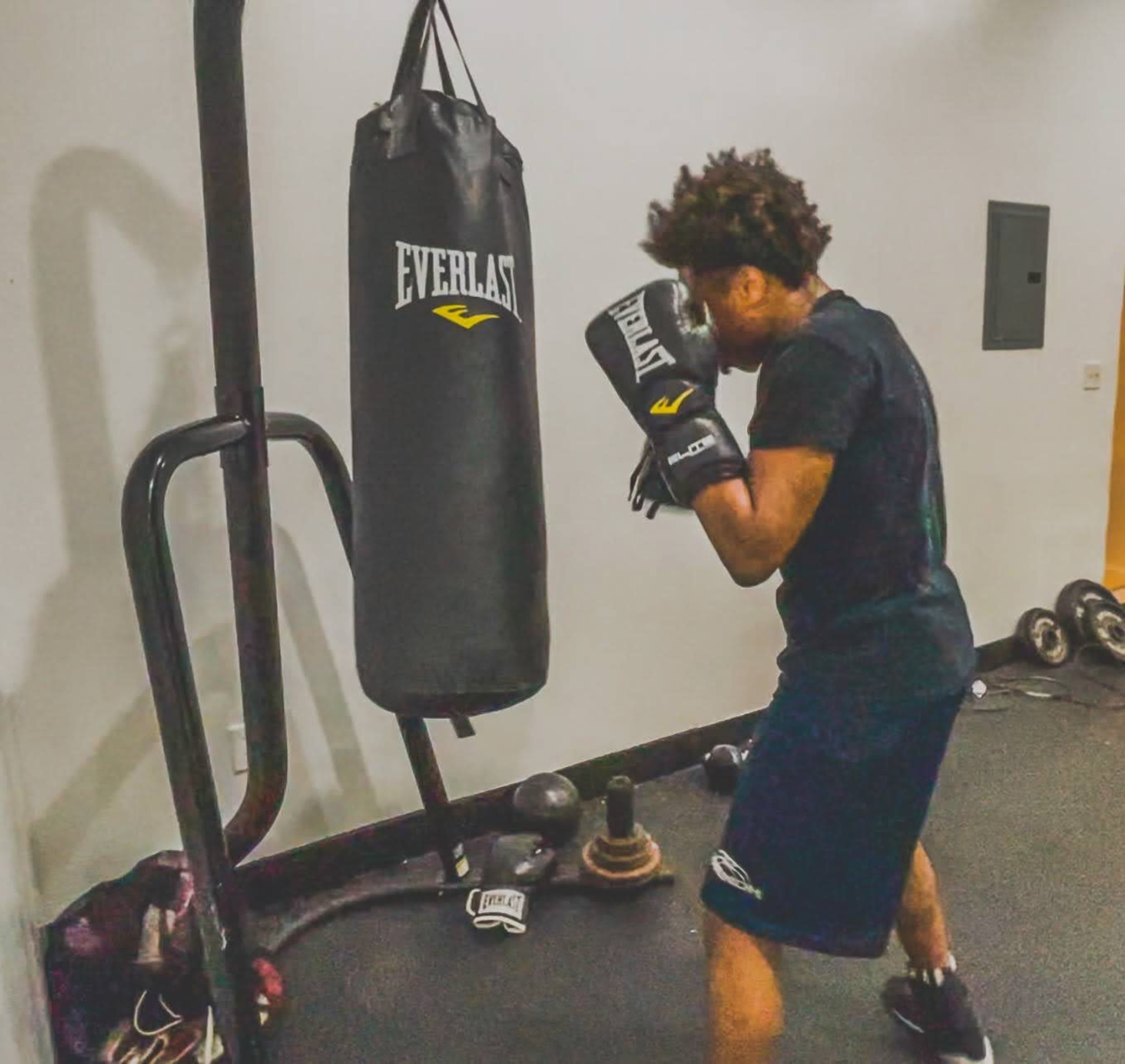 A person is practicing boxing by striking a heavy bag in a gym.