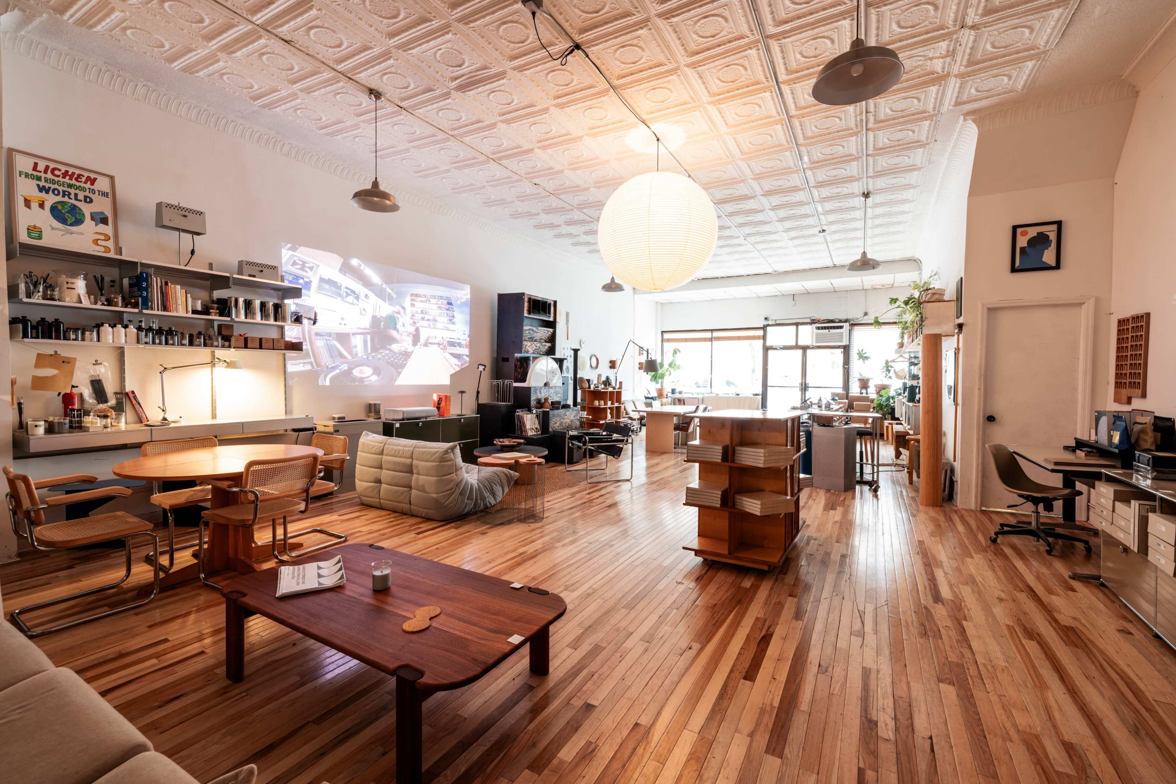 The spacious room features wooden flooring, contemporary furniture, and a large projection screen on one wall.