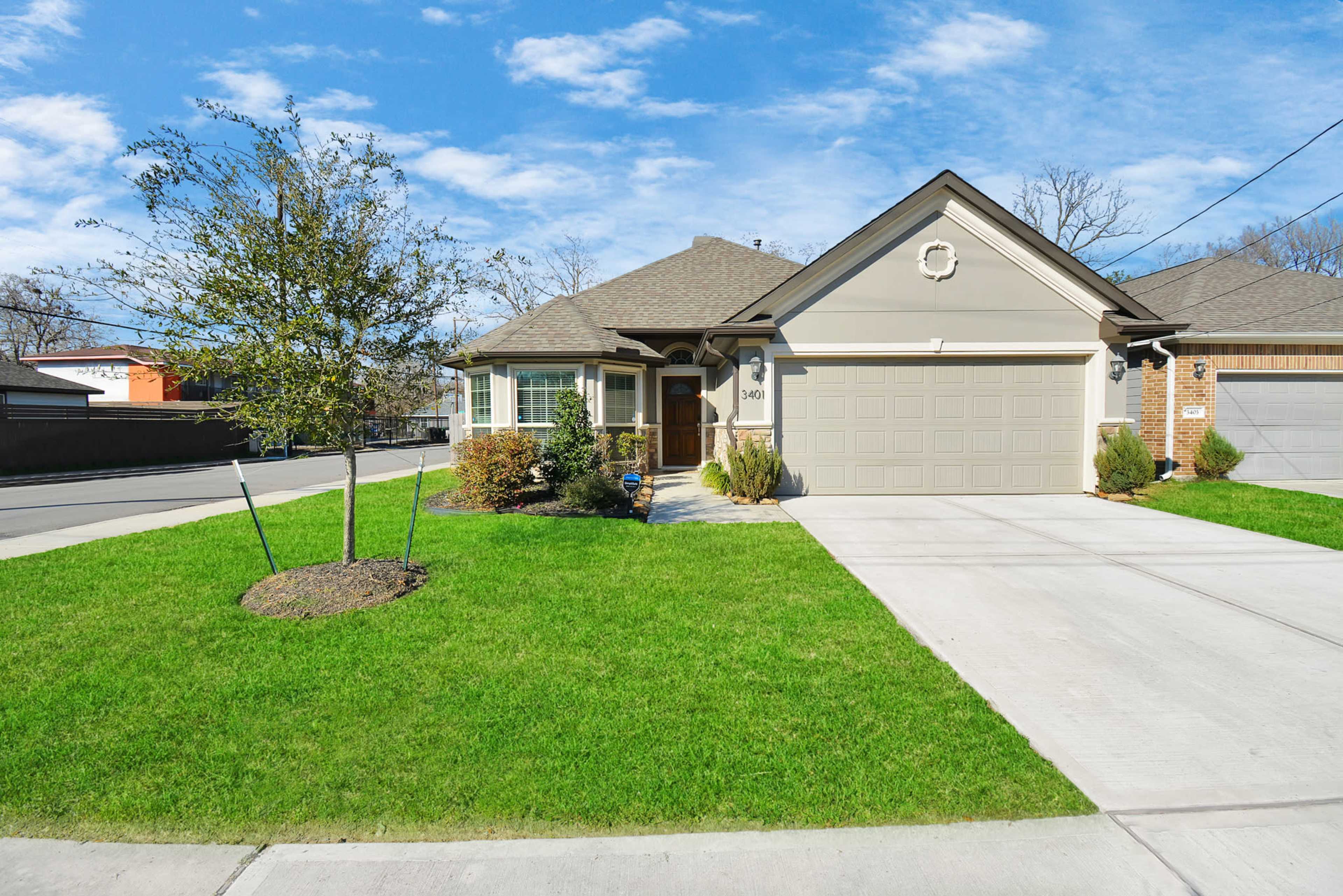 A single-story house with a garage and landscaped front yard is shown on a clear day.