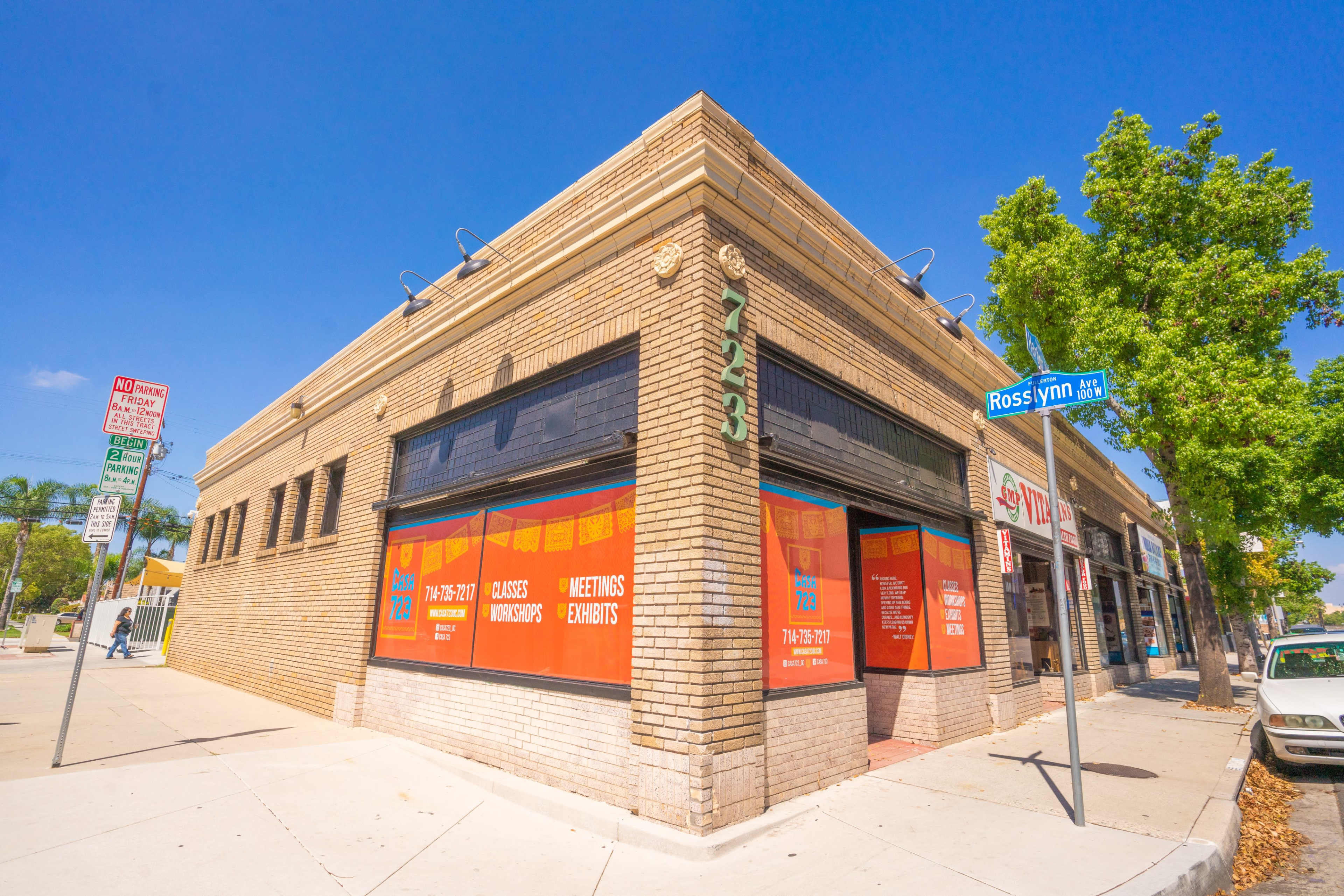 A commercial building with large orange signs advertising meetings and events sits at the corner of Rosslyn Street on a clear day.