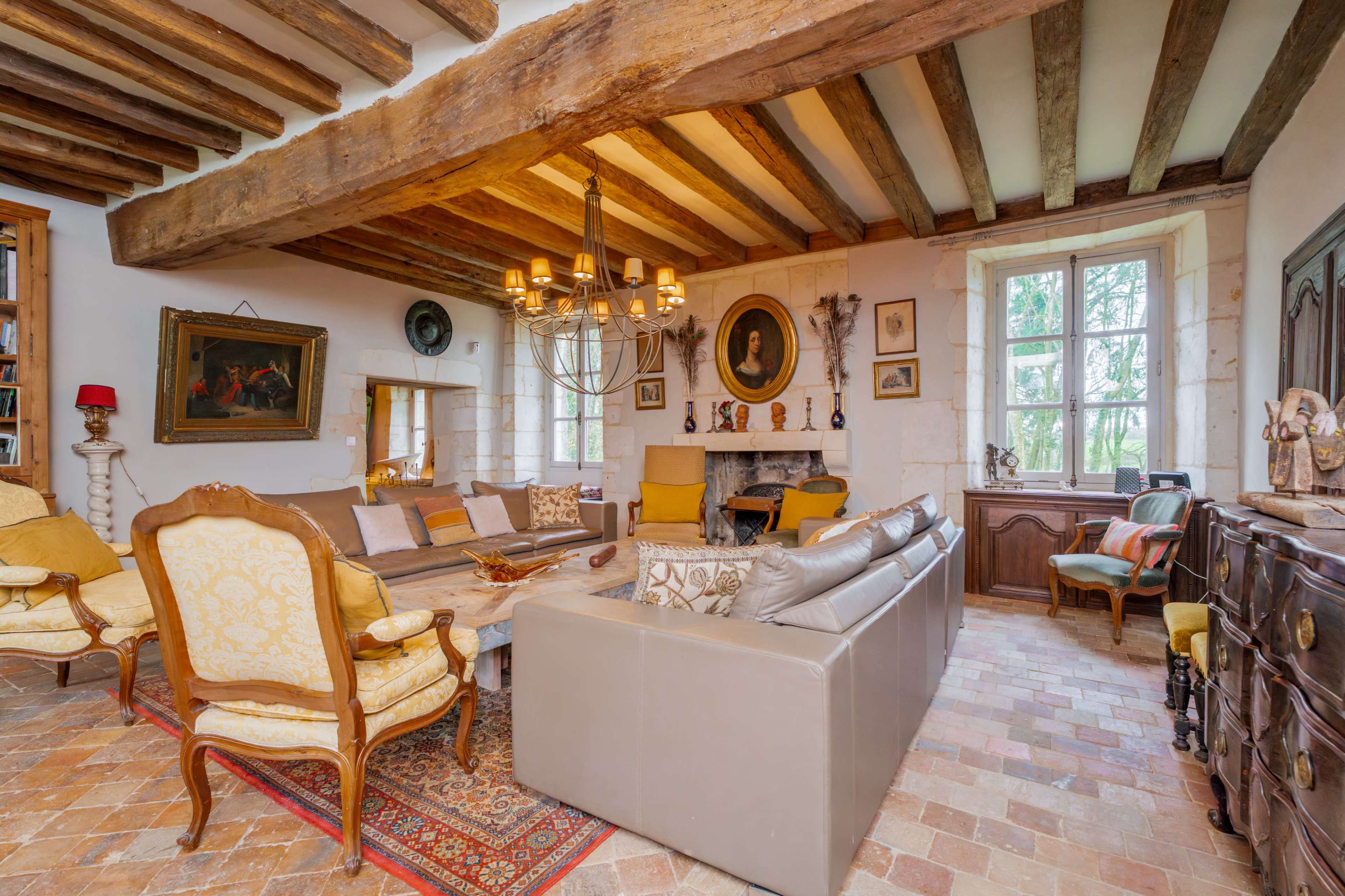 The living room features wooden beams, a chandelier, and a mix of vintage furniture, creating a cozy atmosphere.