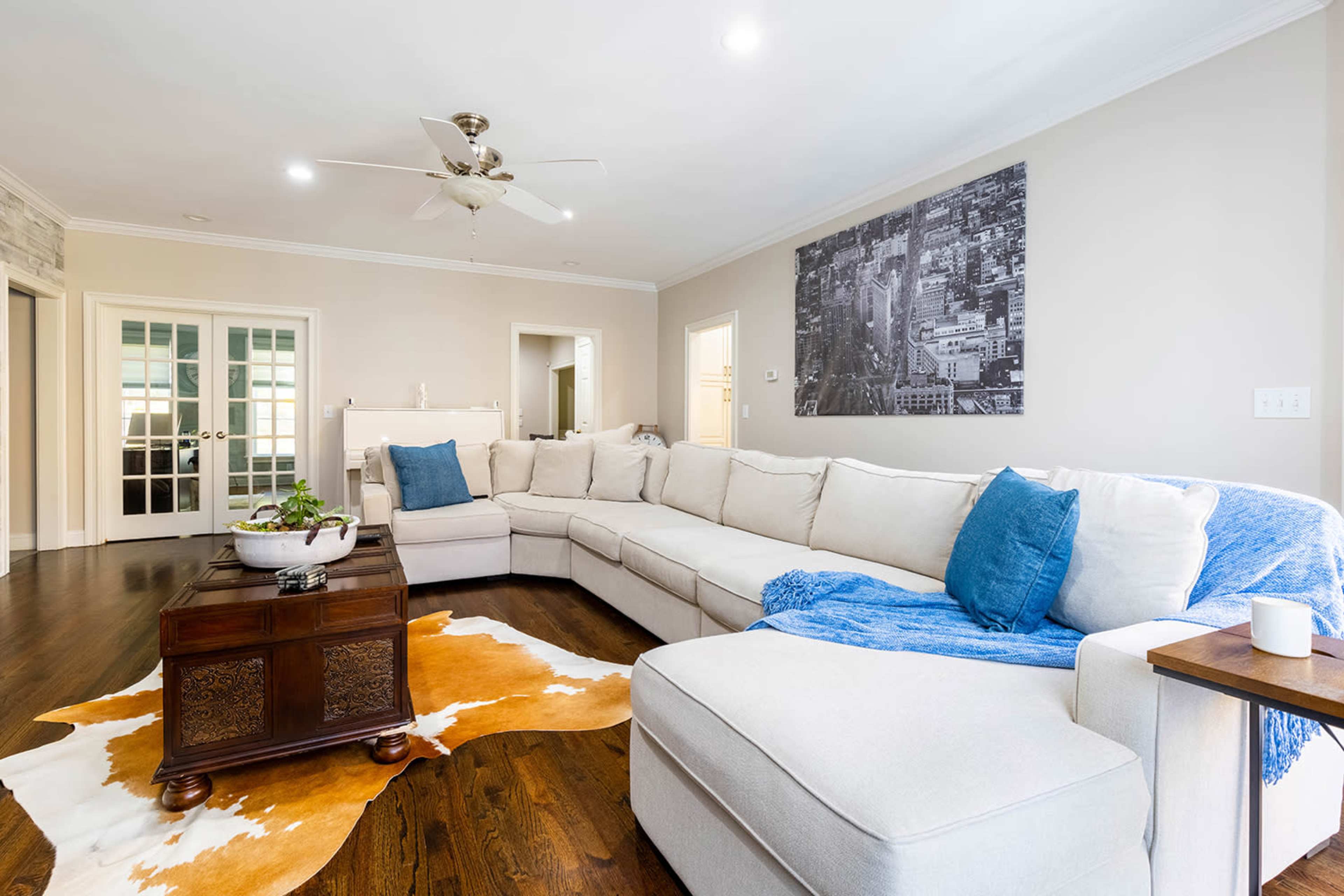 A spacious living room features a large sectional sofa, a wooden coffee table, and a decorative cowhide rug.