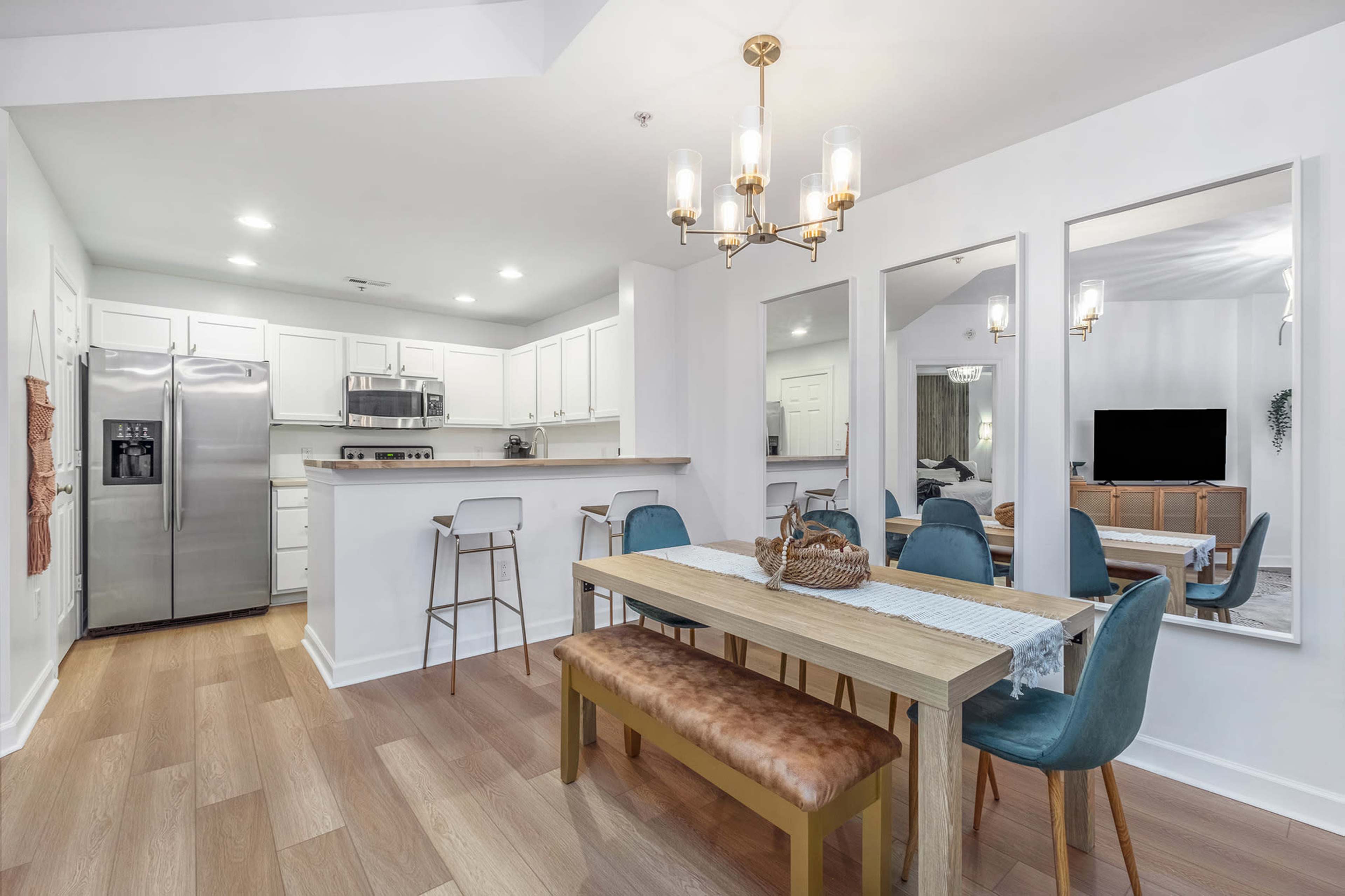 A modern dining area with a wooden table, blue chairs, and an open kitchen in the background.