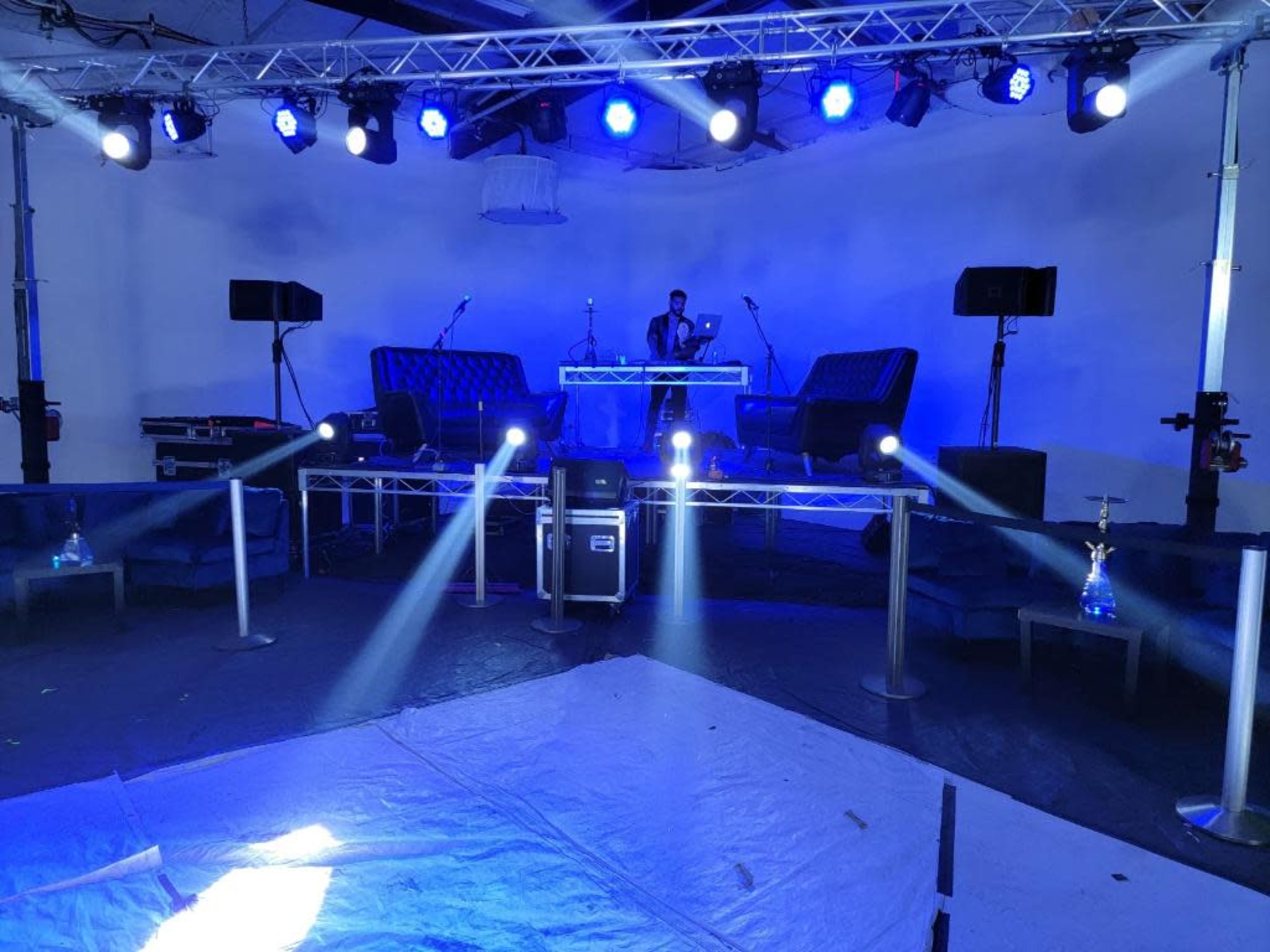 A stage setup with blue lights, two sofas, and audio equipment arranged for an event.