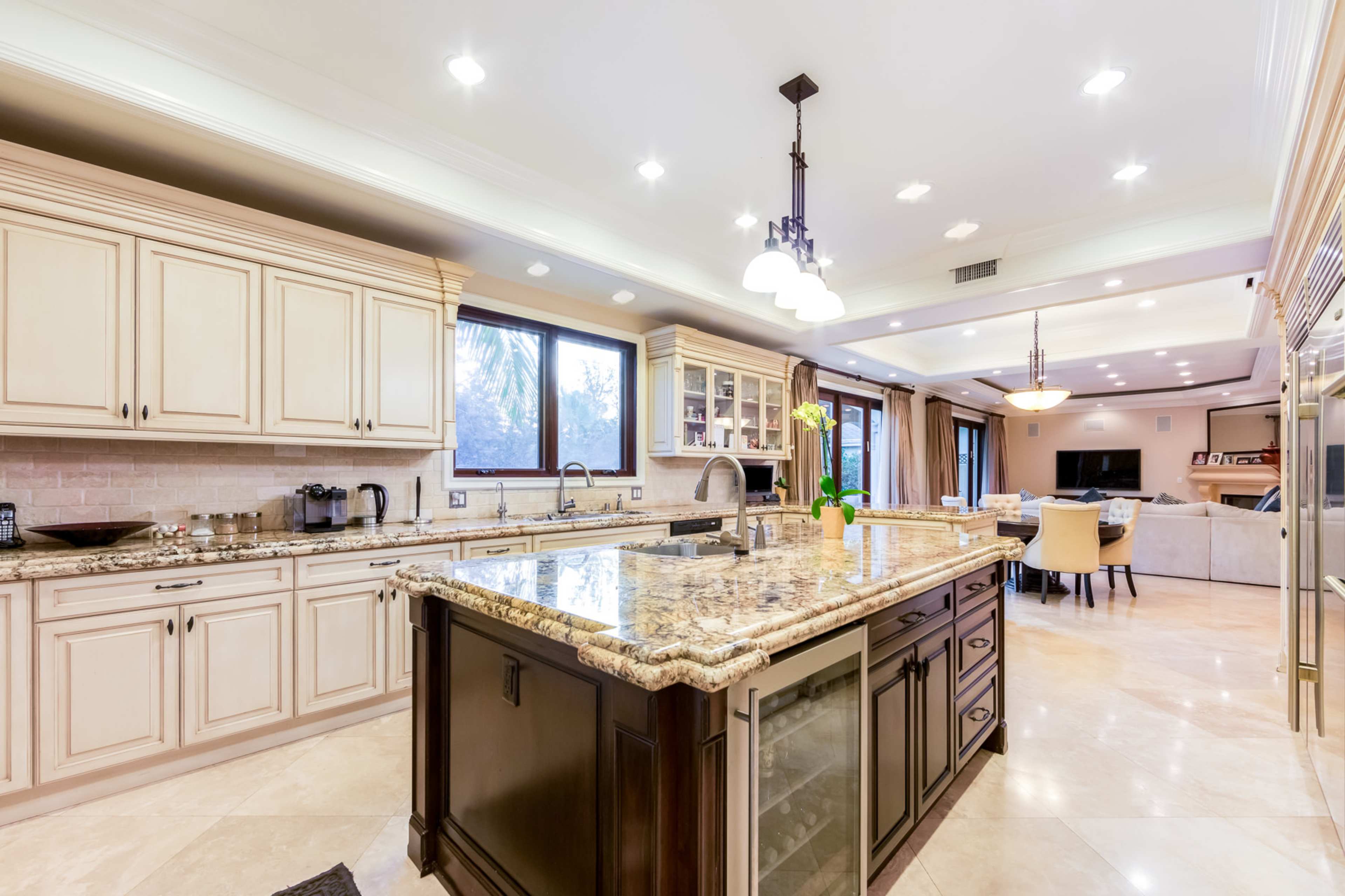 A spacious kitchen features a large island with granite countertops, cream-colored cabinets, and modern appliances.