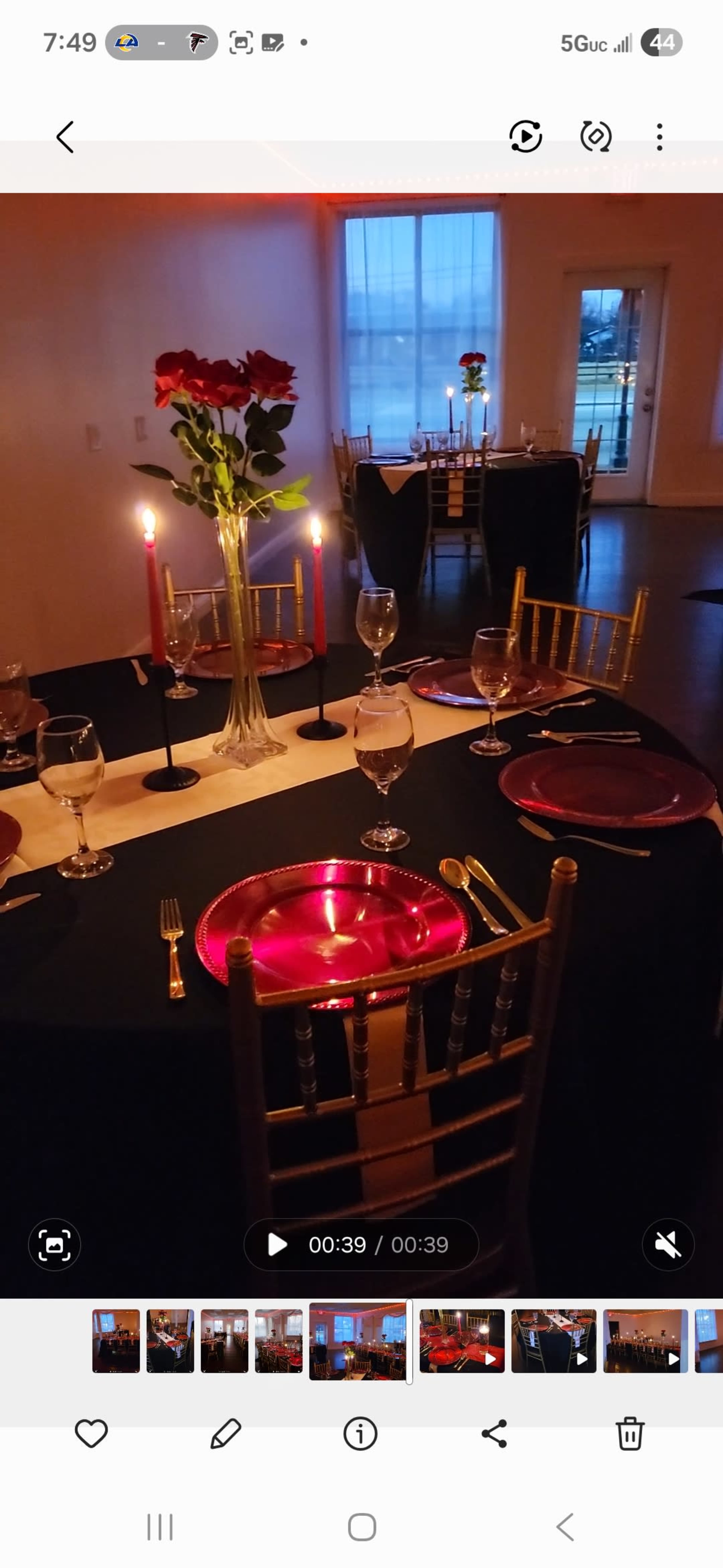 The image shows a beautifully set dining table with red roses in a vase, lit candles, and elegant glassware, surrounded by chairs in a softly lit room.