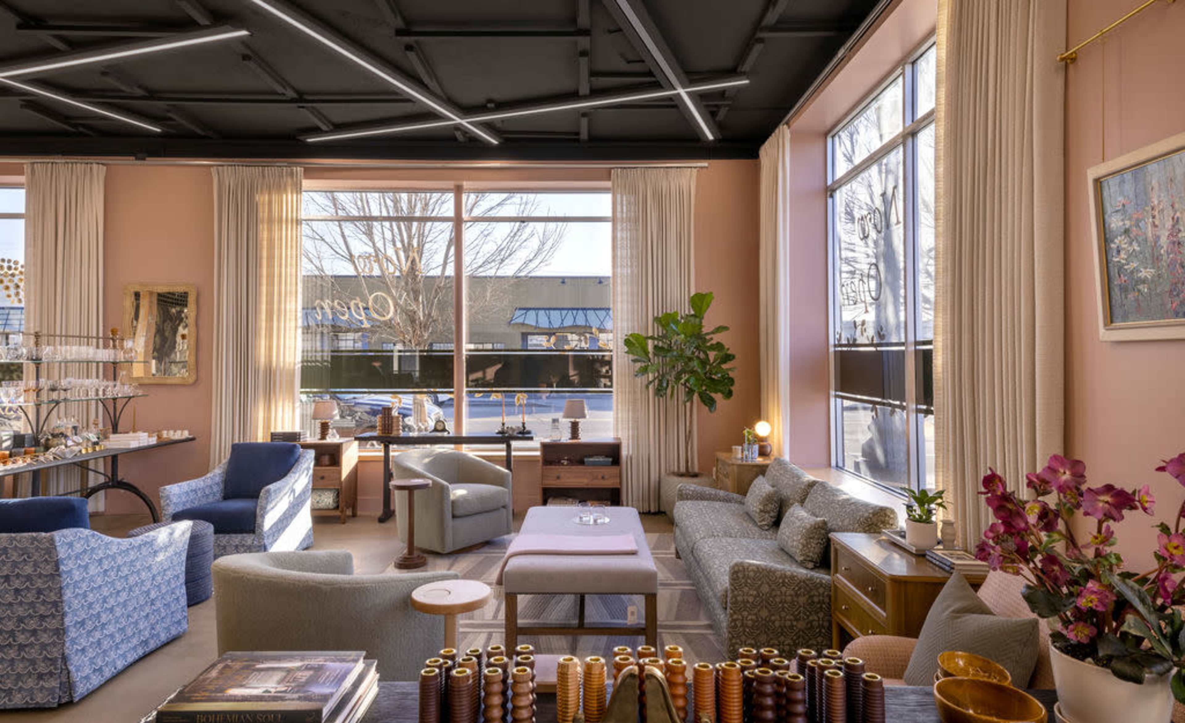 A cozy café interior with light-colored walls, large windows, and a mix of comfortable seating arrangements, including sofas and chairs.