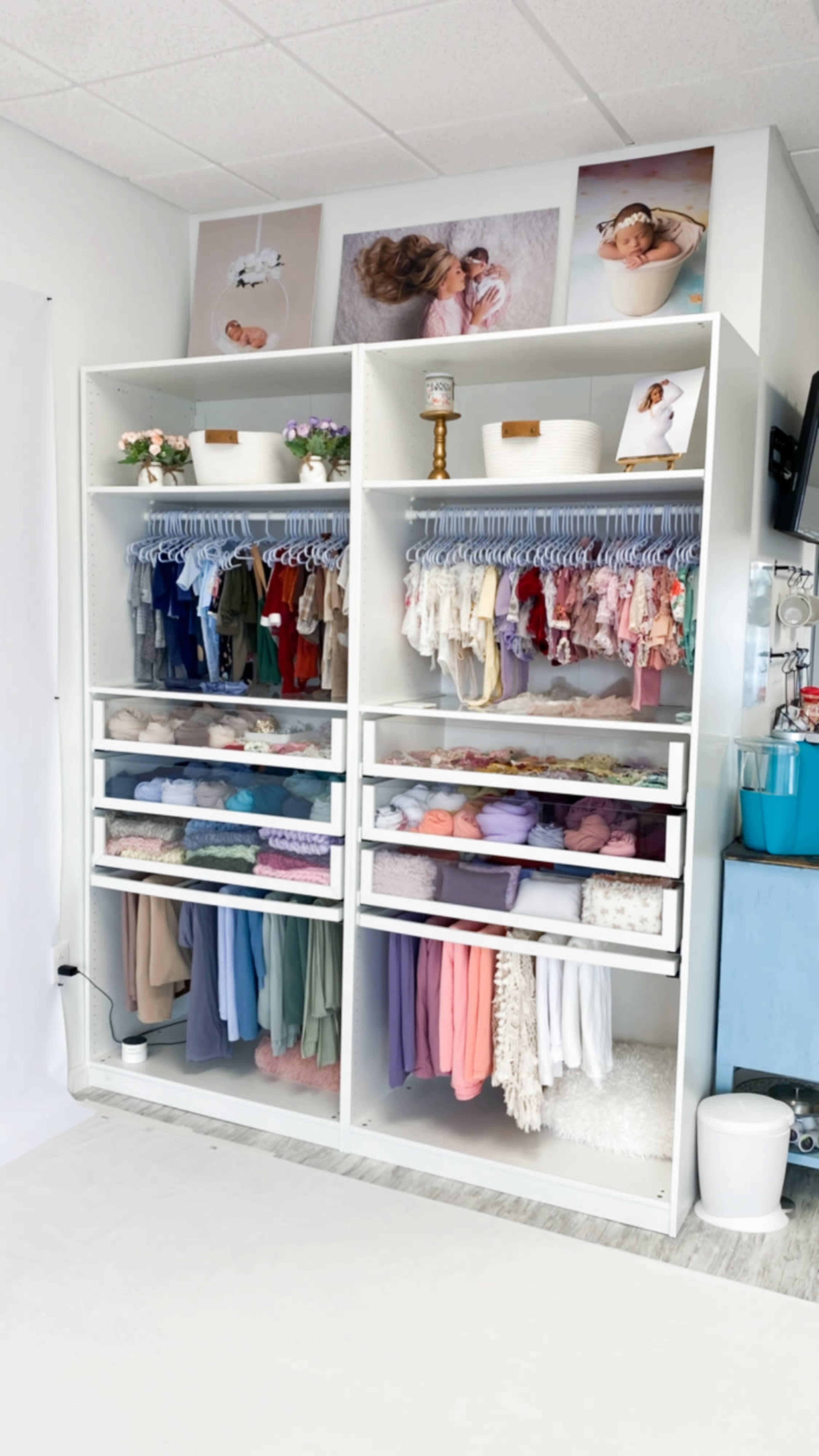 The image shows a neatly organized clothing rack with multiple shelves displaying various garments and accessories, including pastel colors and fabrics, alongside decorative items on the top shelf.