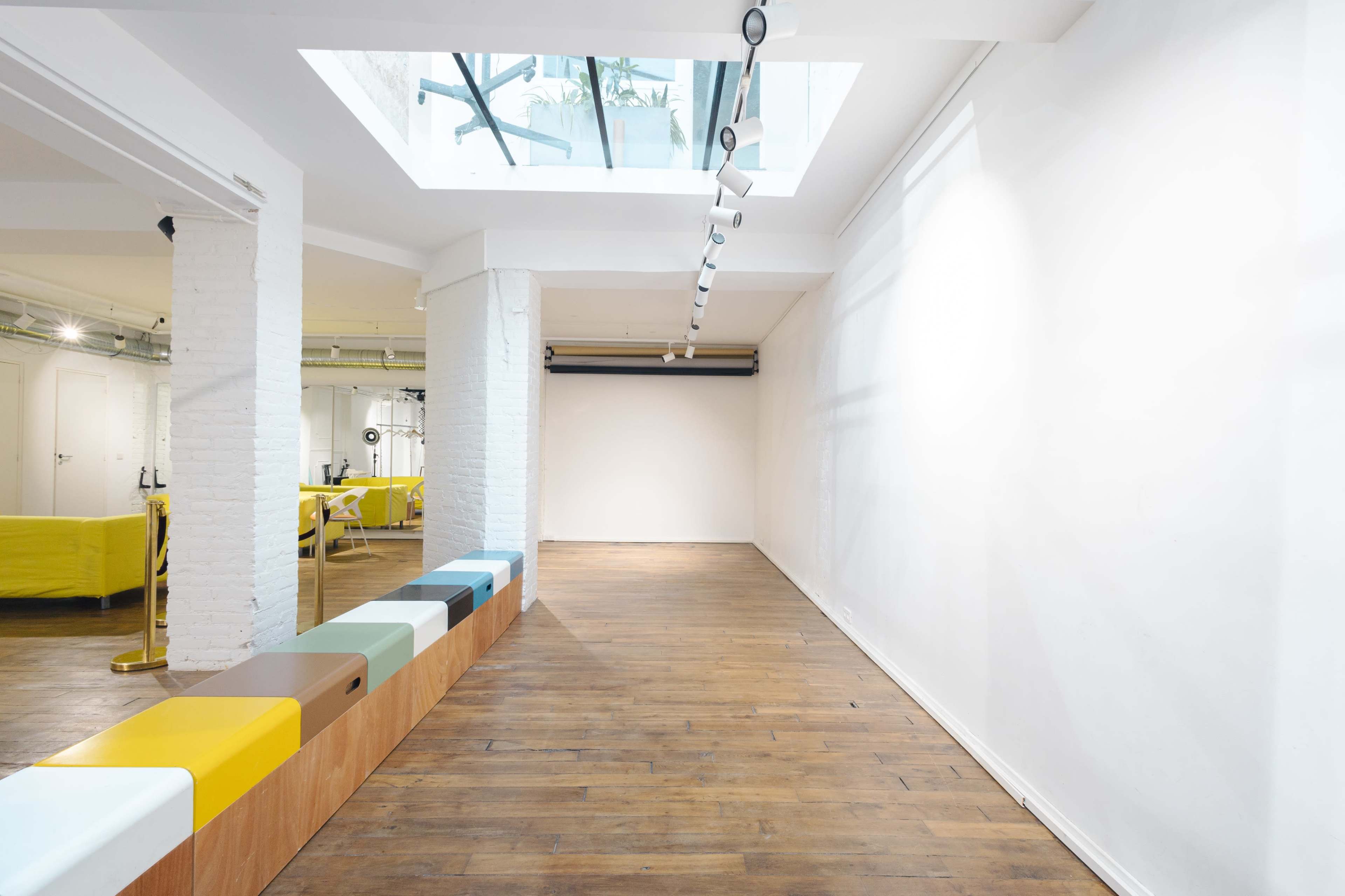 A spacious, empty room with a wooden floor, white walls, and a skylight overhead.