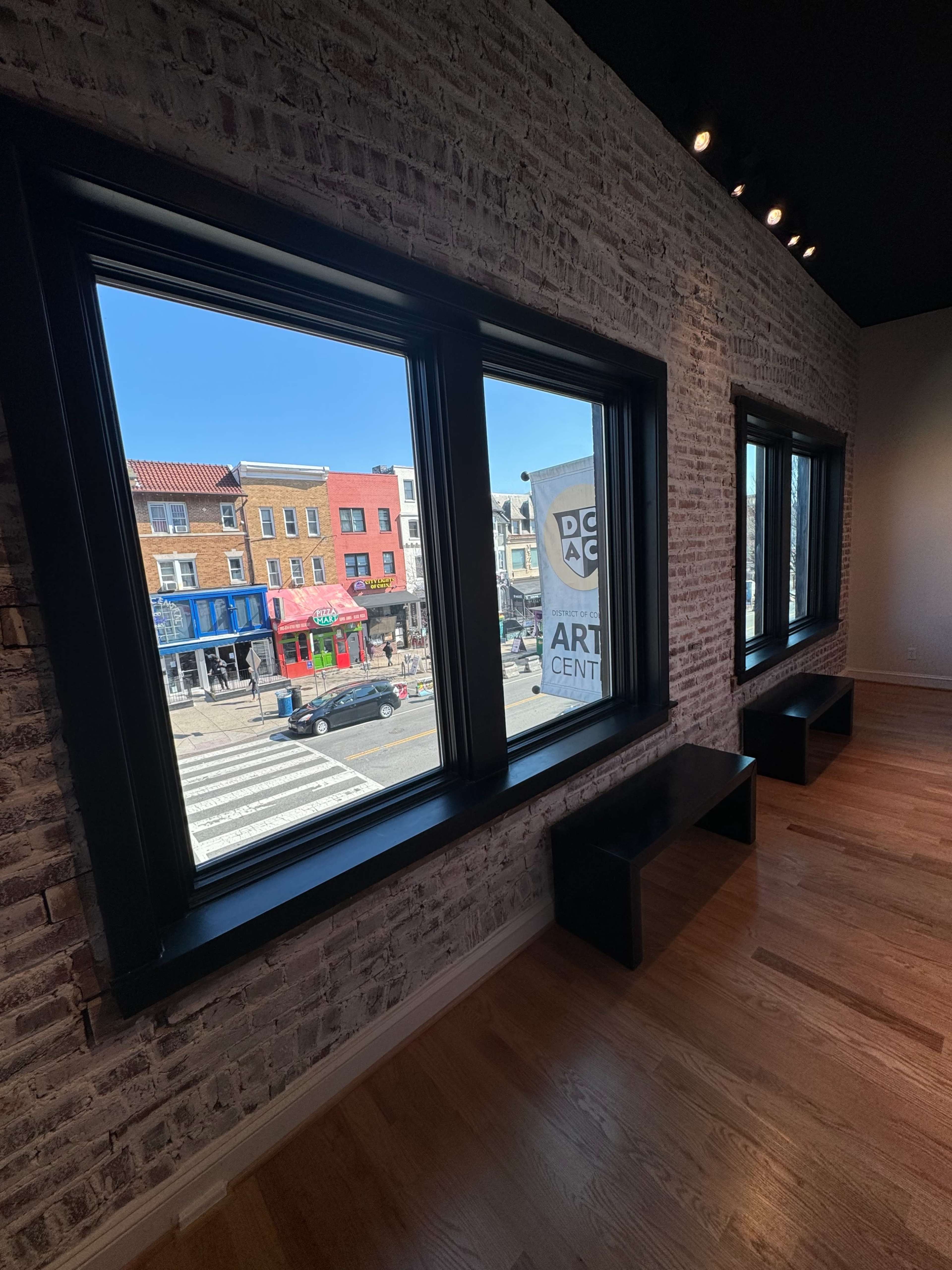 Large windows looking out onto a vibrant street scene with several colorful storefronts.