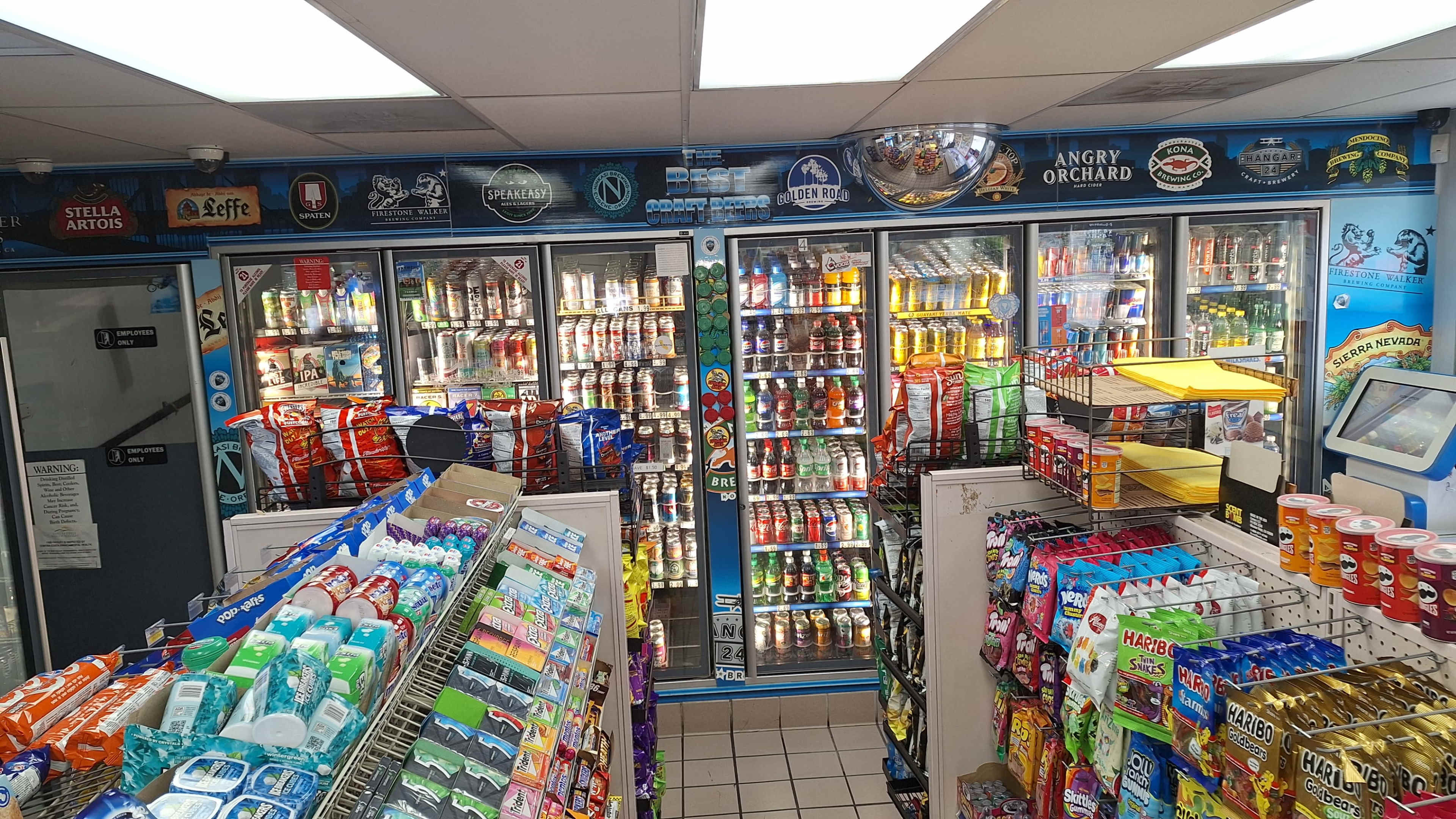 The image shows the interior of a convenience store with shelves stocked with snacks, drinks, and a variety of items for sale.