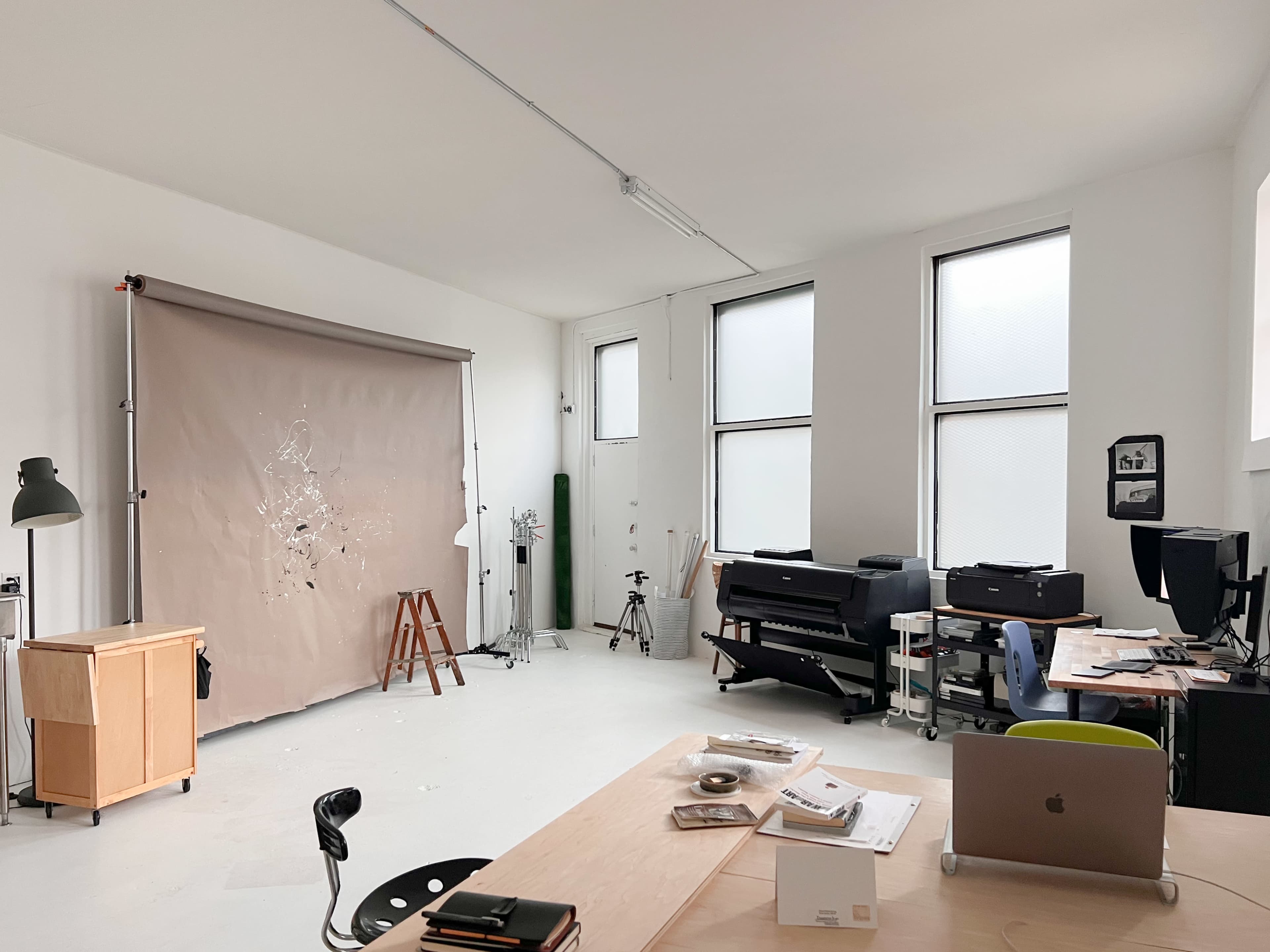 A spacious studio set up with a backdrop for photography, a desk with materials, and various equipment for creative work.